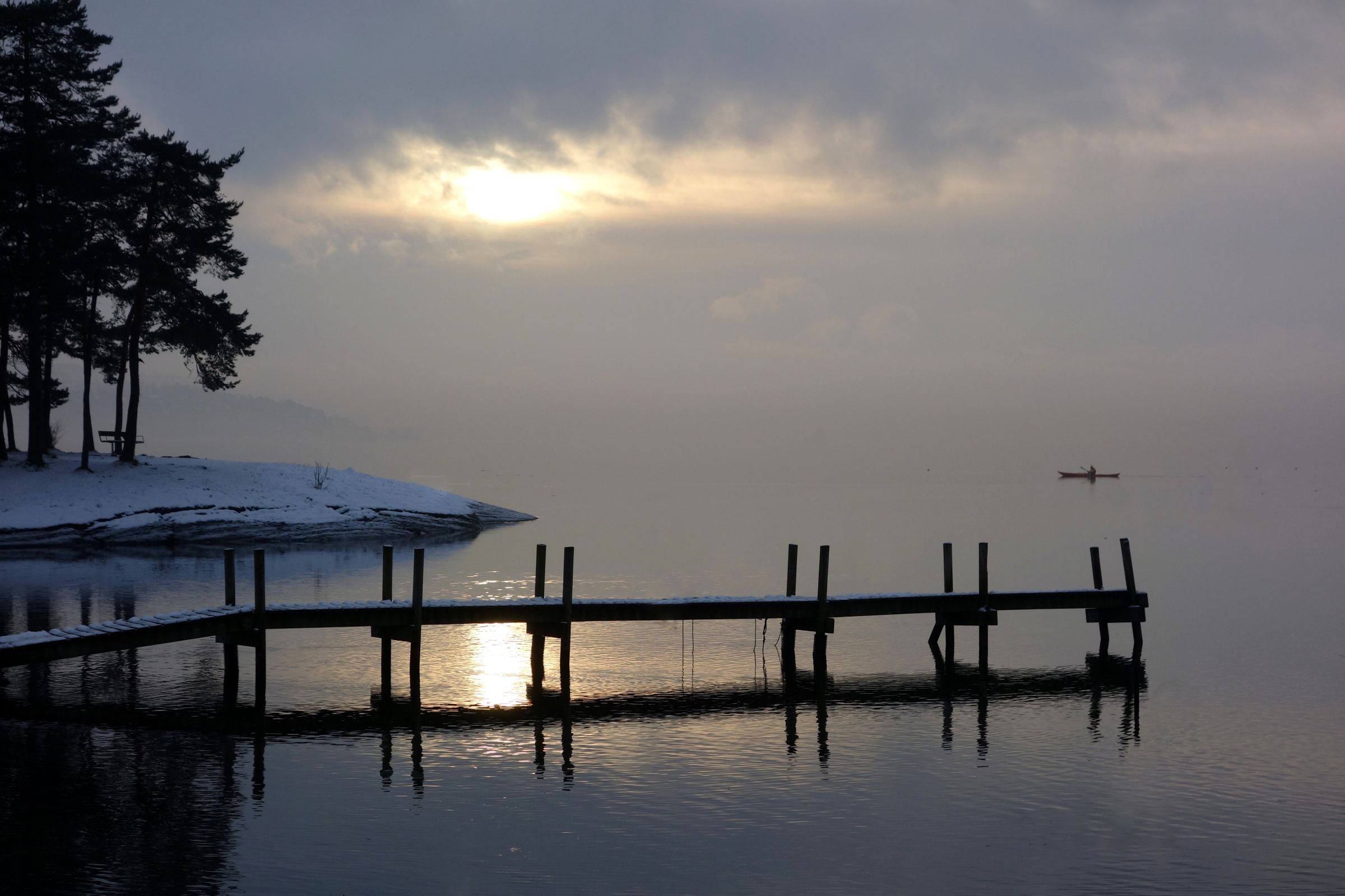 Overskyet himmel på vinteren med en liten brygge ut mot havet.