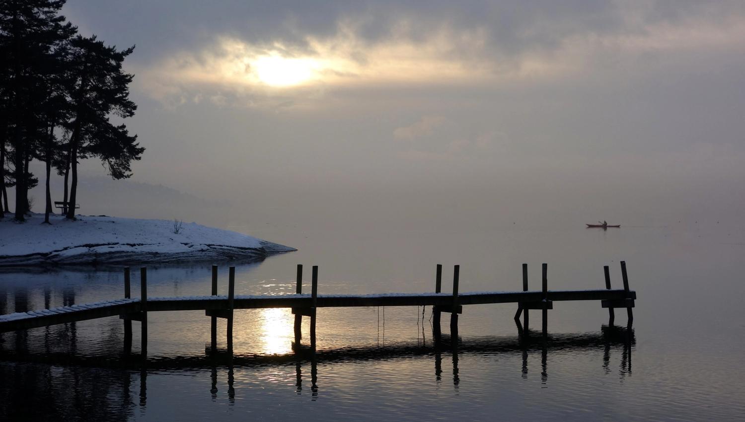 Overskyet himmel på vinteren med en liten brygge ut mot havet.