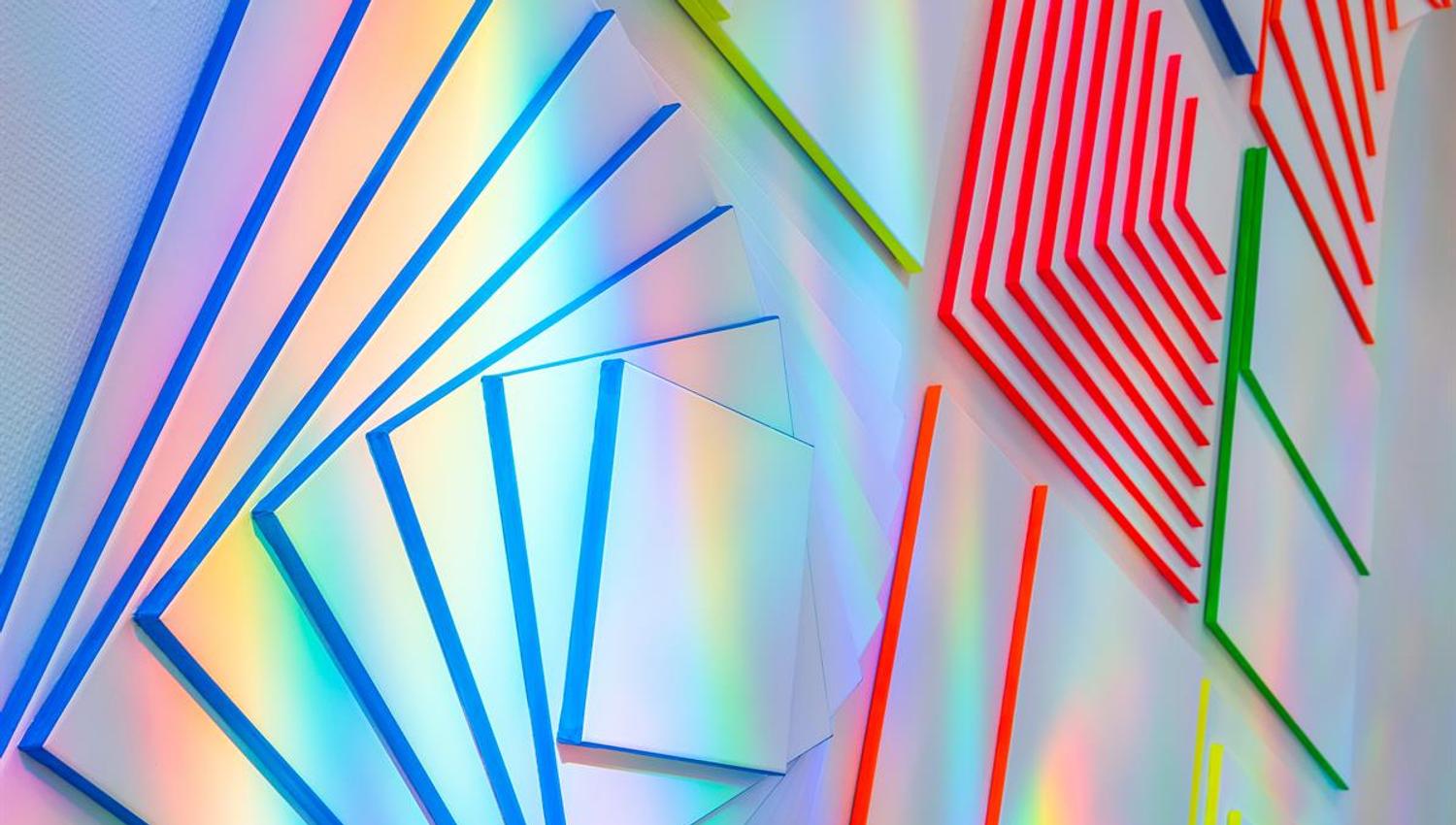 Kunstutstilling Kunstbanken - Fargerike geometriske kunstpaneler med lysrefleksjoner.