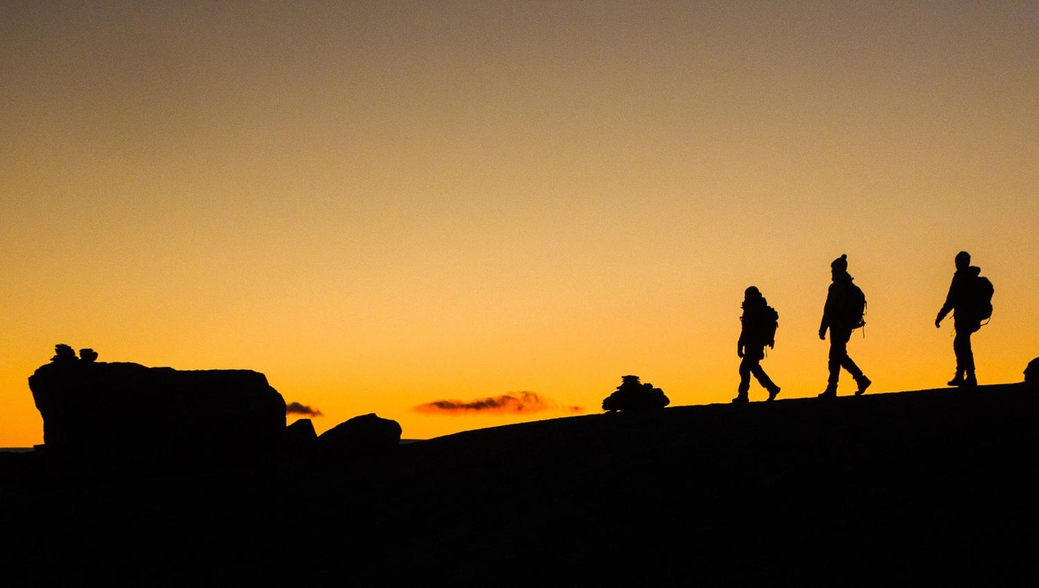 Silhouettes of hikers at sunset on the mountain plateau near Trolltunga in Hardanger.