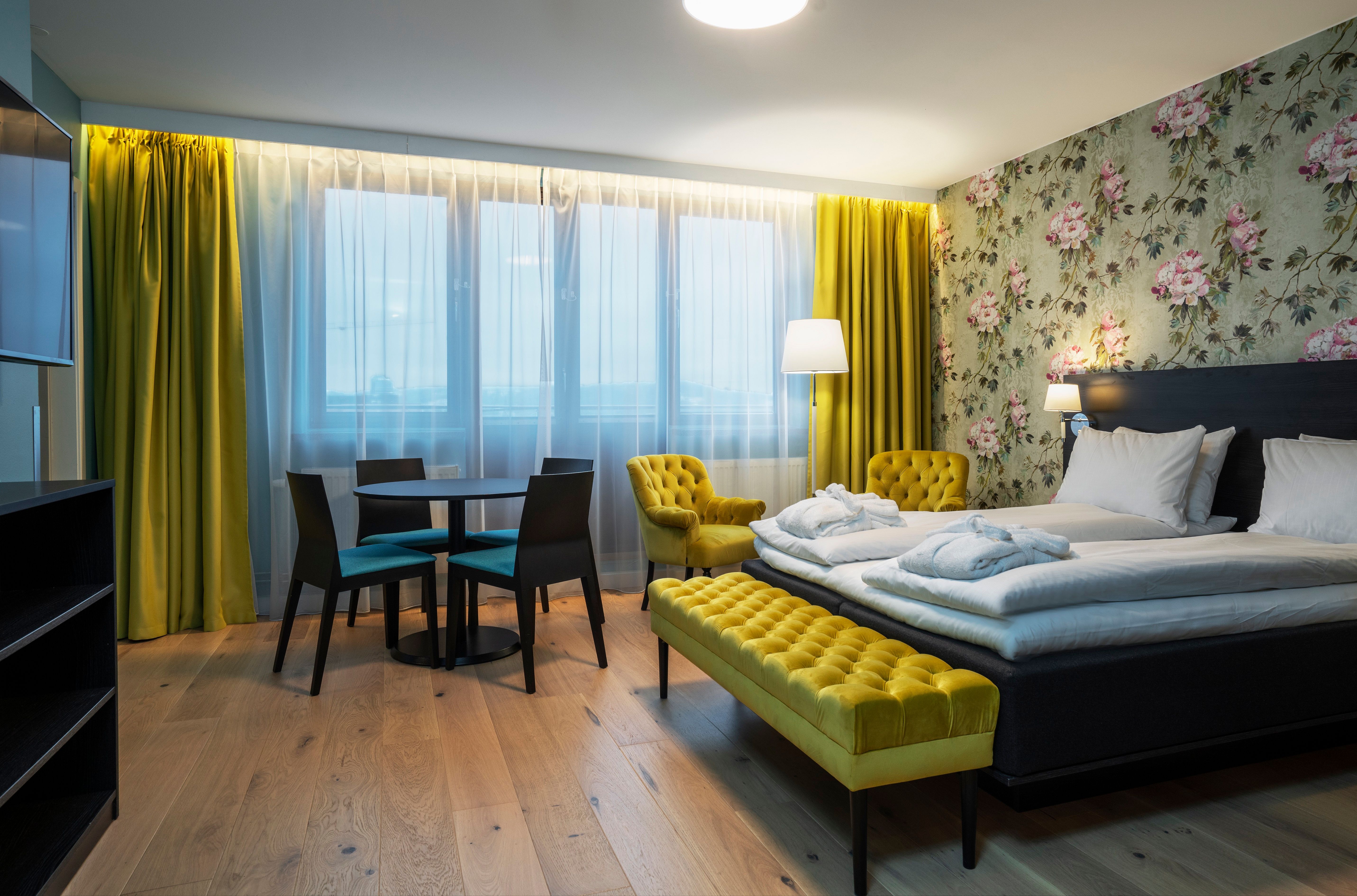 Rom med dobbetseng. Møblement og gardiner i gult.Tregulv. Thon Hotel Slottsparken, Oslo. Foto