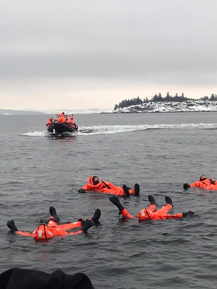 Mennesker i oransje drakter som flyter i sjøen