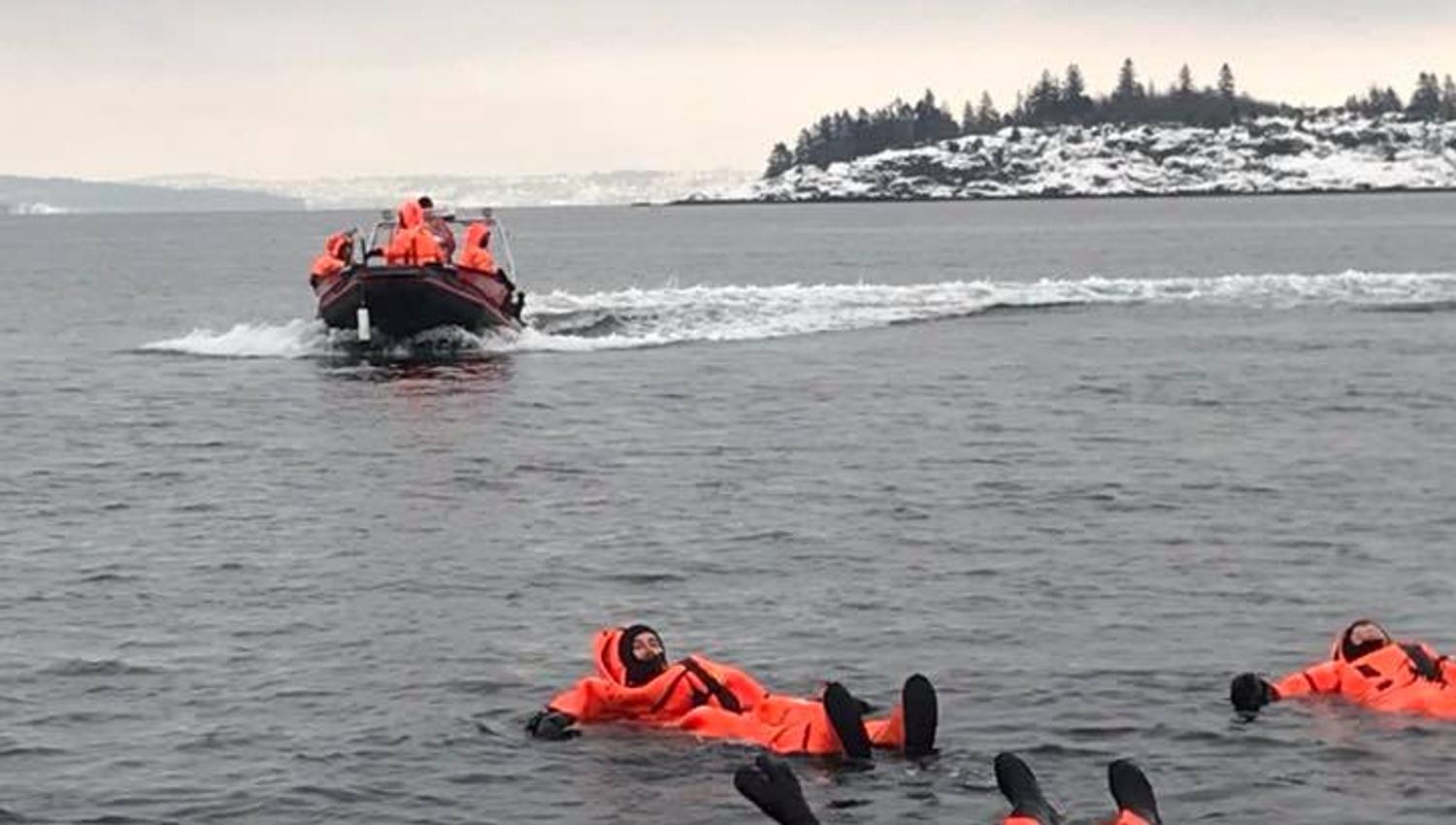Mennesker i oransje drakter som flyter i sjøen