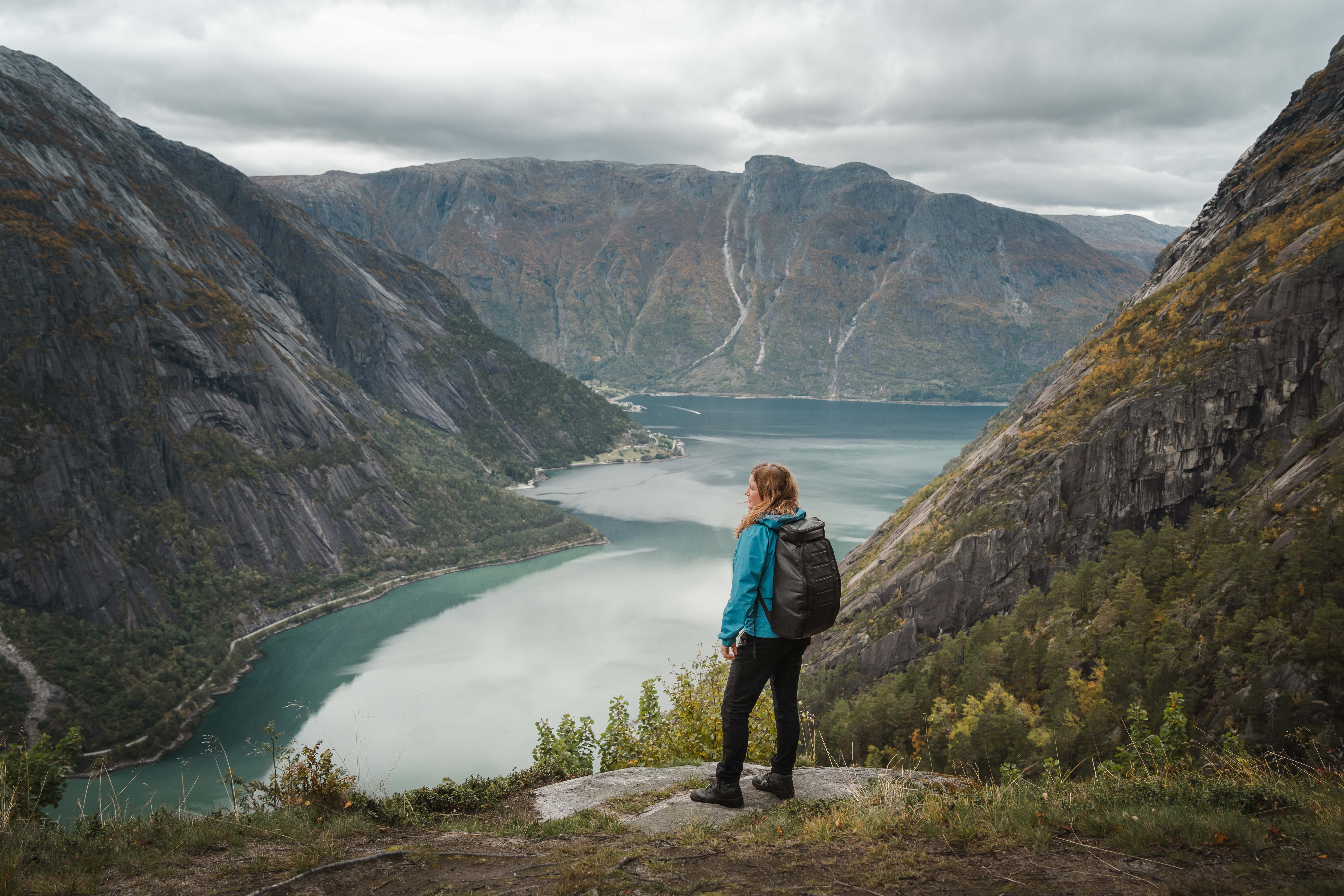 En kvinne i blå jakke står ved utsiktspunktet Kjeåsen og ser ned på fjorden.