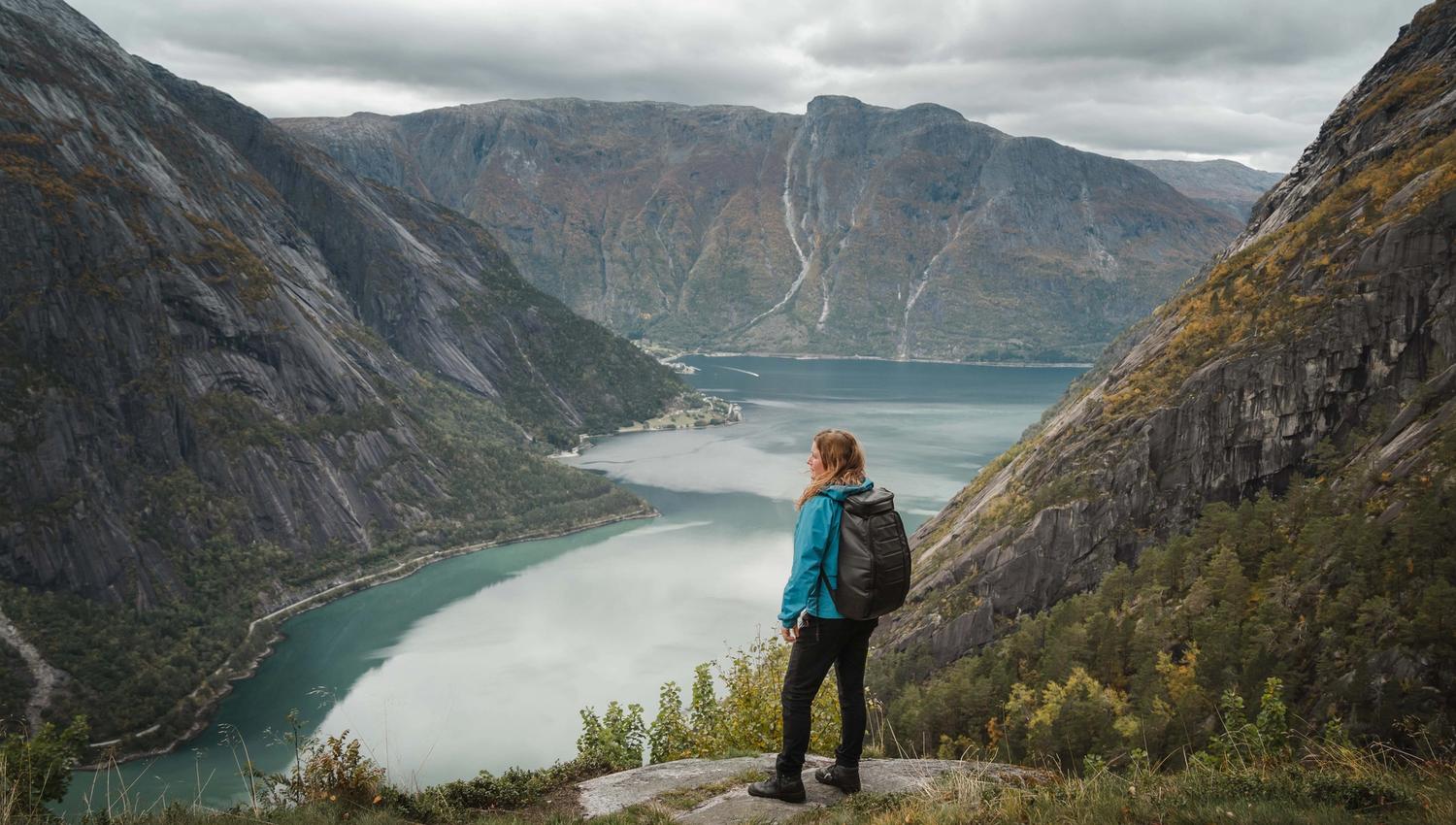 En kvinne i blå jakke står ved utsiktspunktet Kjeåsen og ser ned på fjorden.