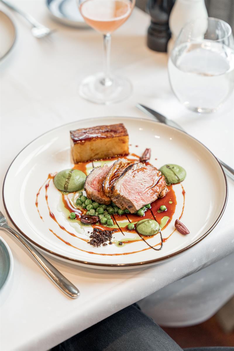 Gourmet dish served from above featuring perfectly cooked meat, colourful sauces and accompaniments.