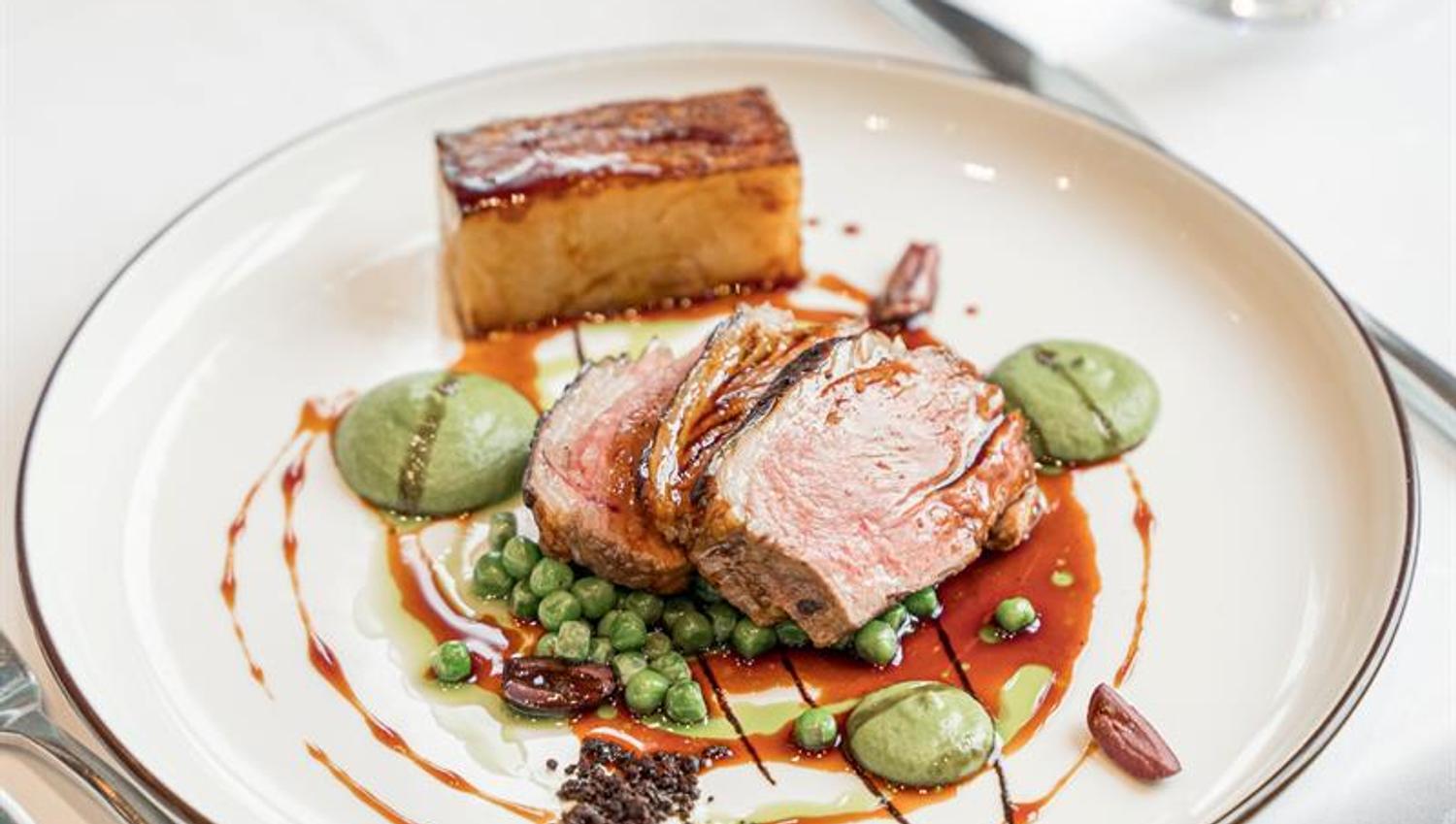Gourmet dish served from above featuring perfectly cooked meat, colourful sauces and accompaniments.