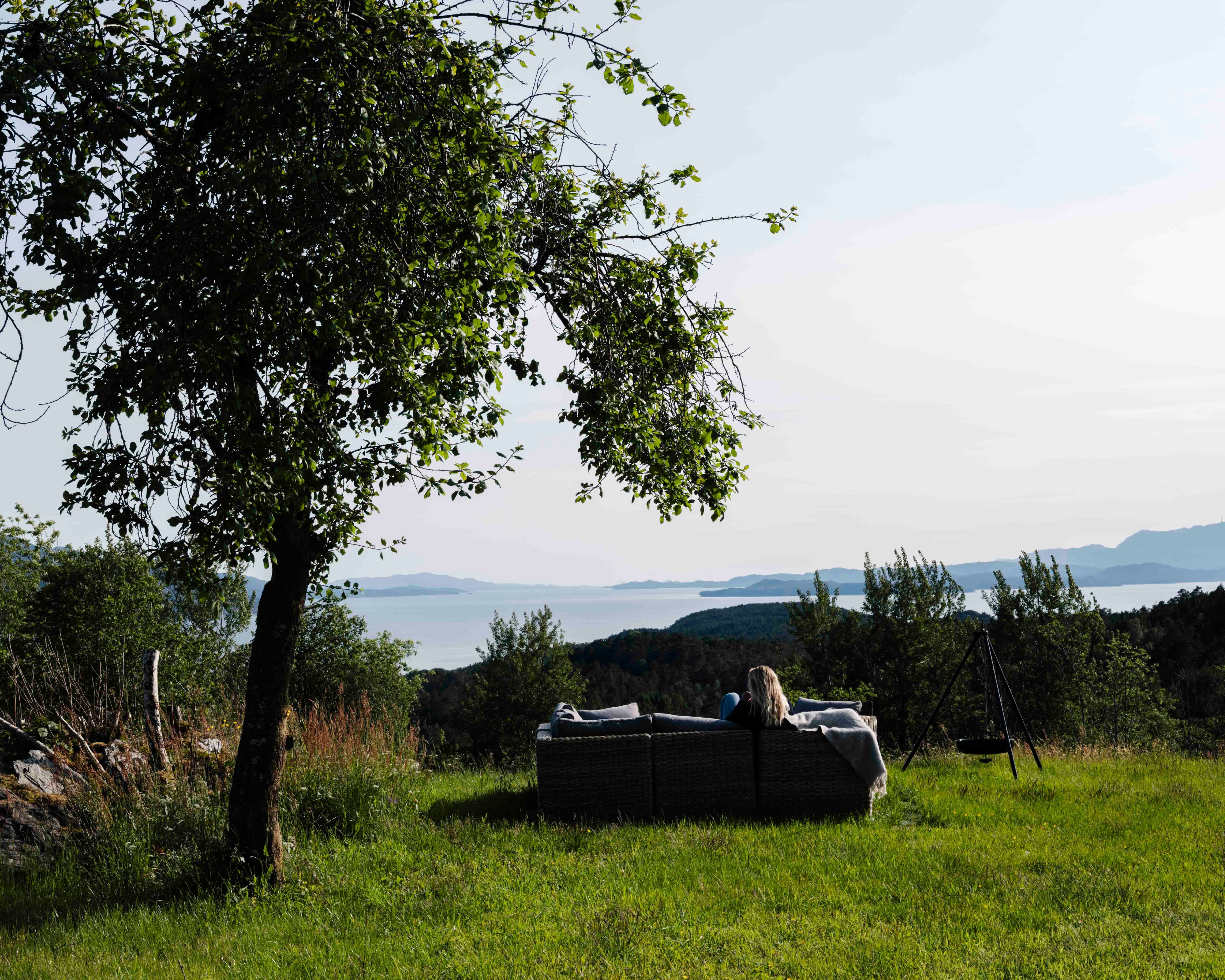 Person nyt utsikta frå utesofaen ved Stigen Fjordlodge i Hardanger.