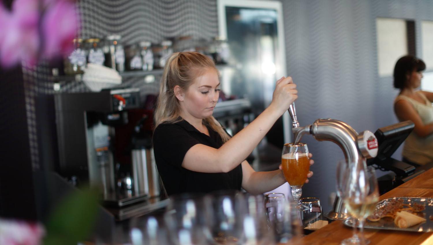 An employee pouring beer into a glass.