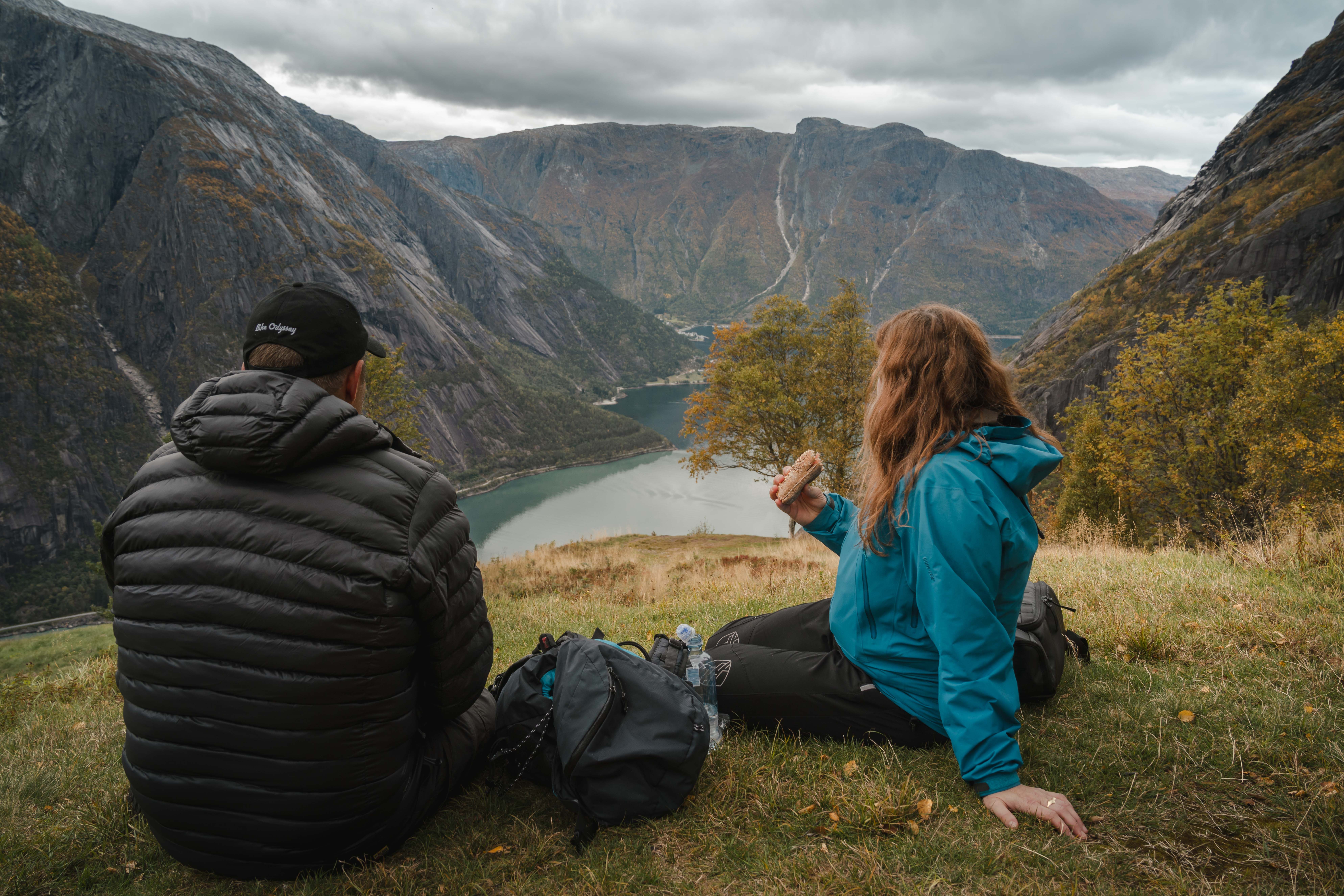 Et par spiser lunsj ved utsiktspunktet Kjeåsen mens de nyter utsikten over fjorden og fjellene.