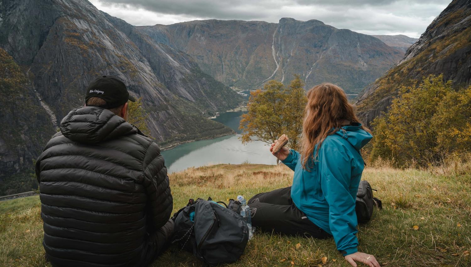 Et par spiser lunsj ved utsiktspunktet Kjeåsen mens de nyter utsikten over fjorden og fjellene.