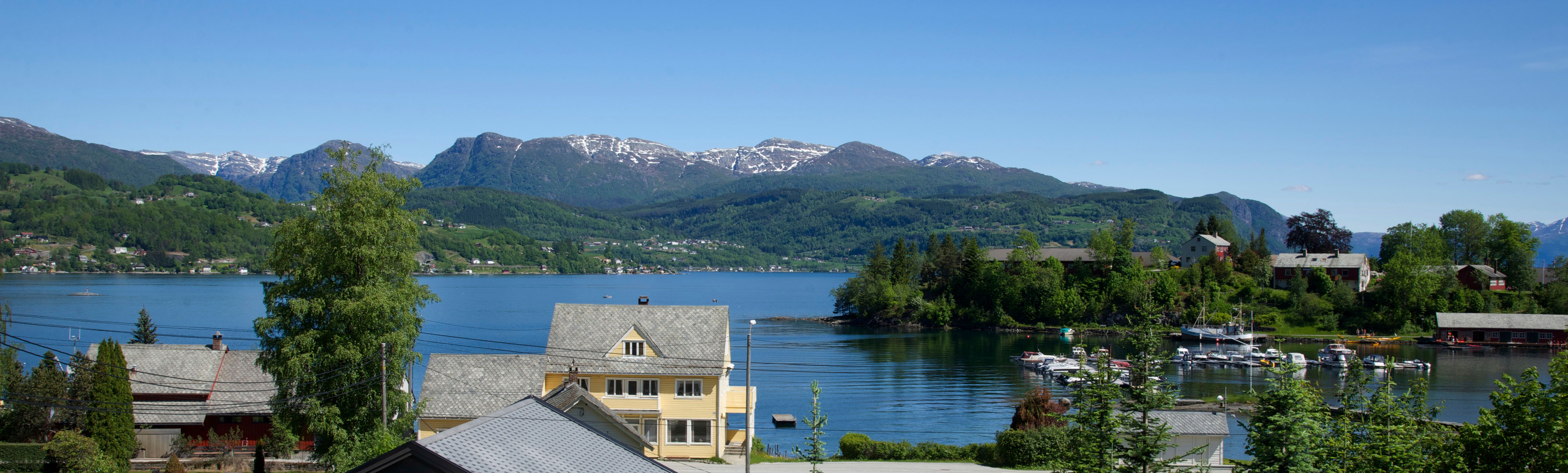 Panoramautsikt over Hardangerfjorden med fjell og bygder sett frå Vågen Rom og Hytteutleige.