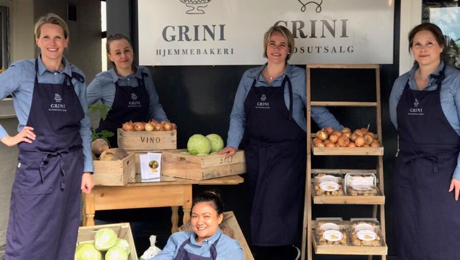 Eiere og ansatte utenfor gårdsbutikken, hyller med ferske grønnsaker