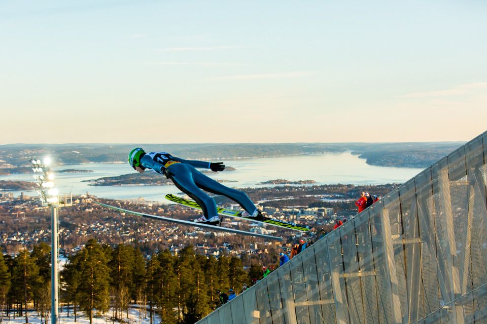 Ski jumper in the air, with the Oslo Fjord in the background.