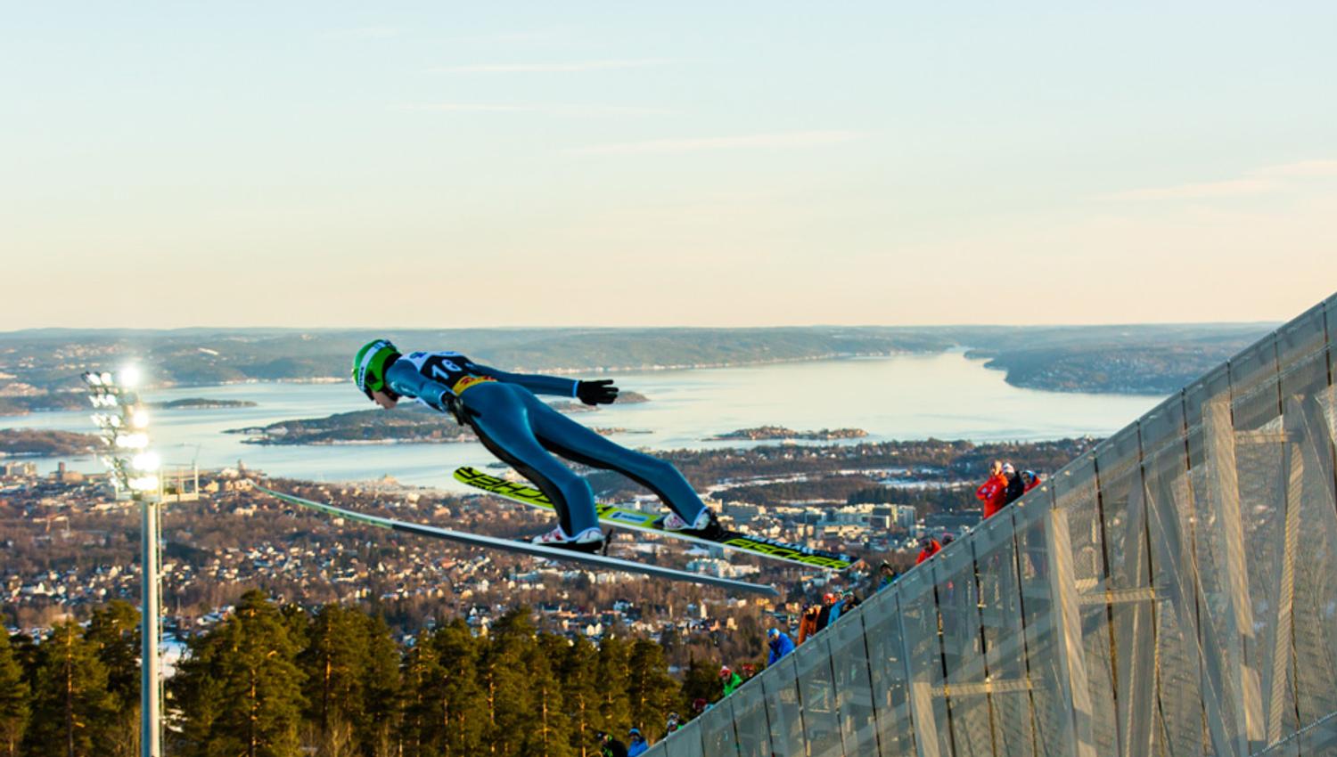 Ski jumper in the air, with the Oslo Fjord in the background.