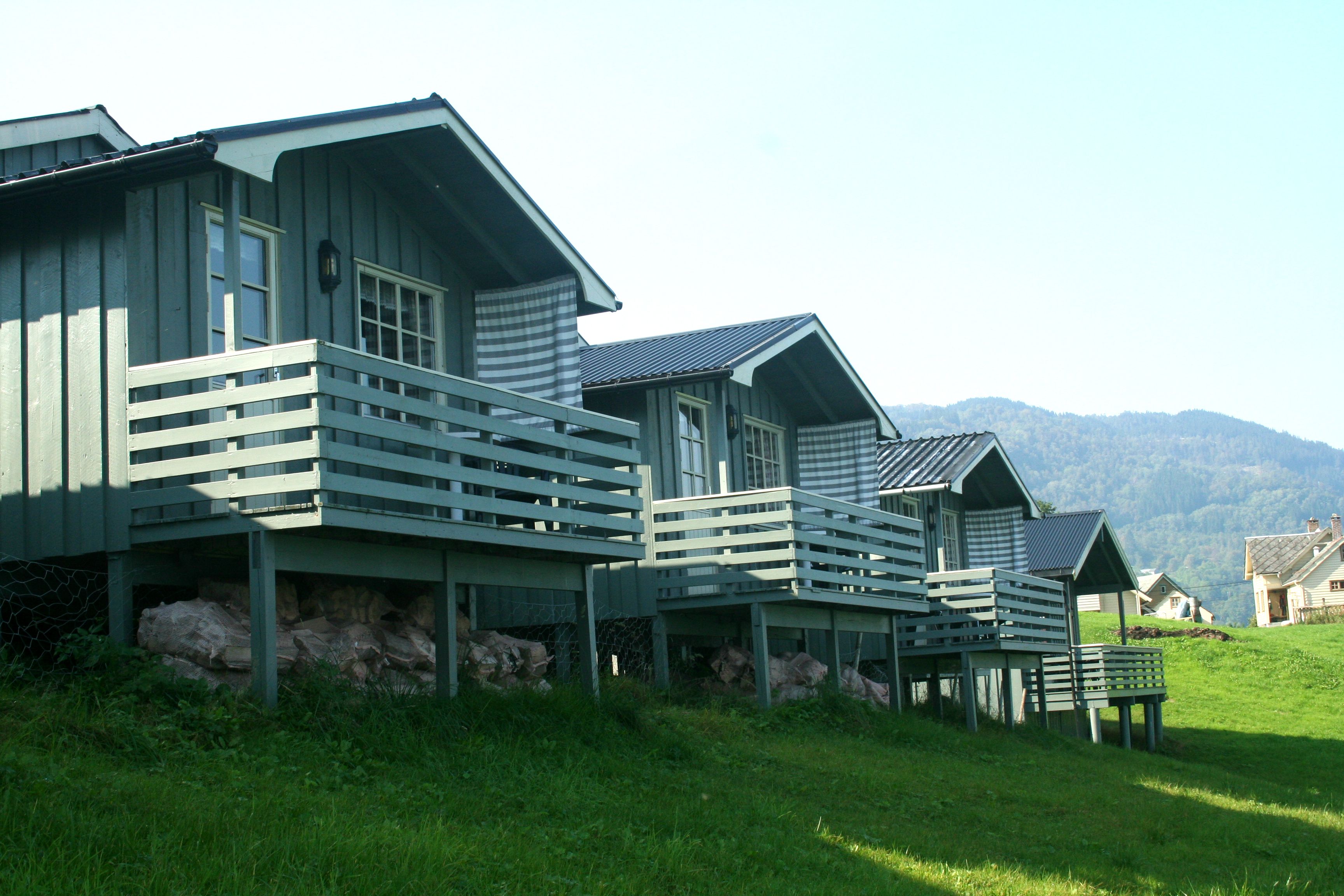Tradisjonelle hytter med veranda og utsikt mot fjell og fjord på Oddland Camping i Hardanger.