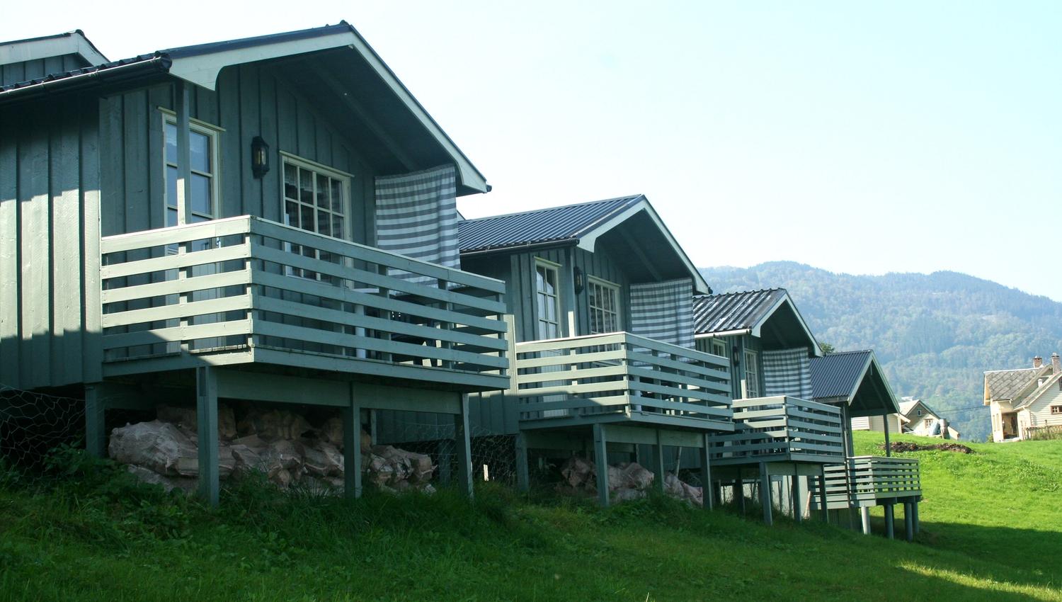 Tradisjonelle hytter med veranda og utsikt mot fjell og fjord på Oddland Camping i Hardanger.