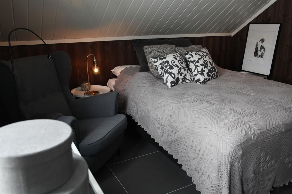 Et soverom med seng, stoler og dempet belysning.