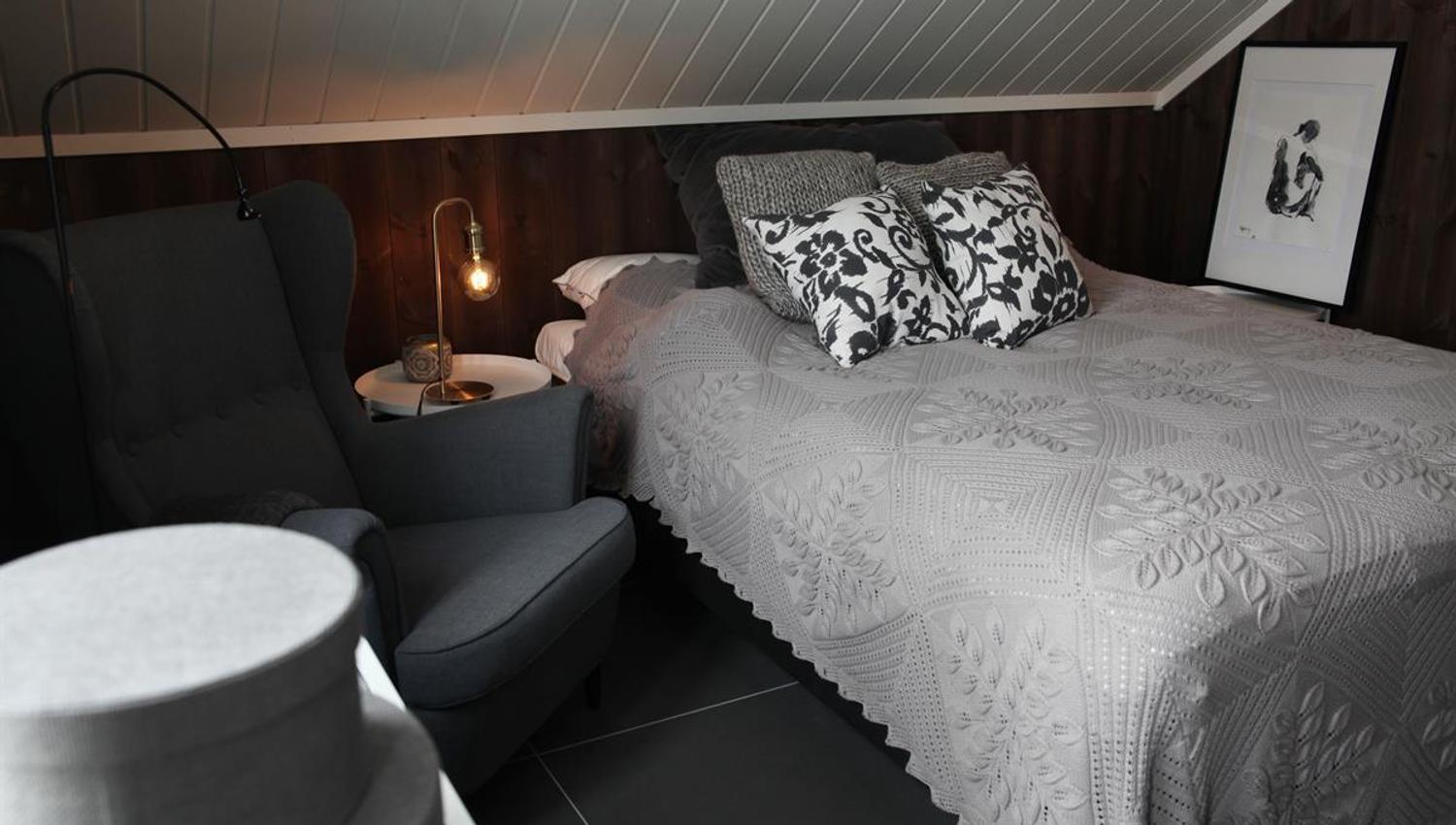 Et soverom med seng, stoler og dempet belysning.