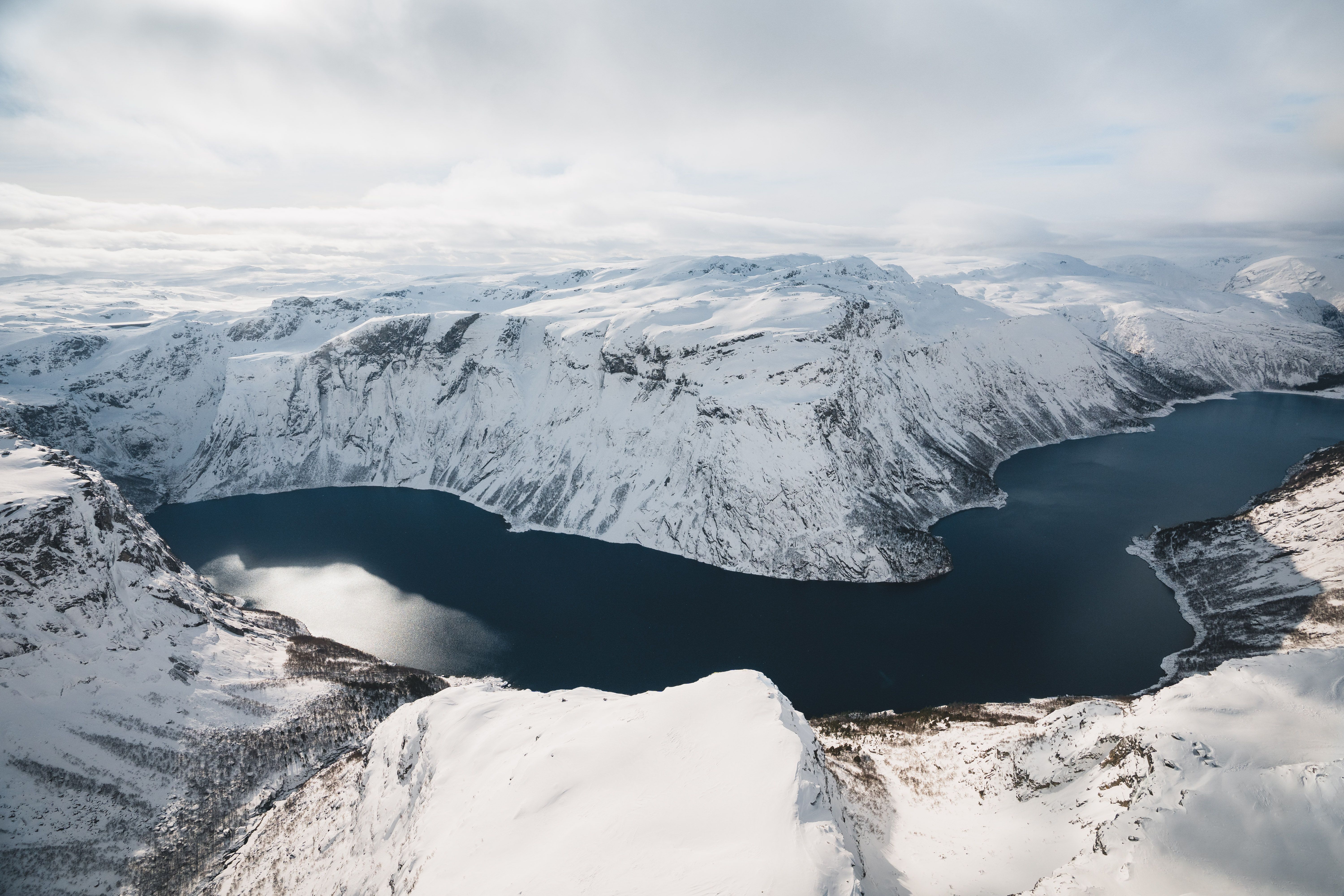Oversiktsbilde over Hardangerfjorden med snøkledde fjell rundt.