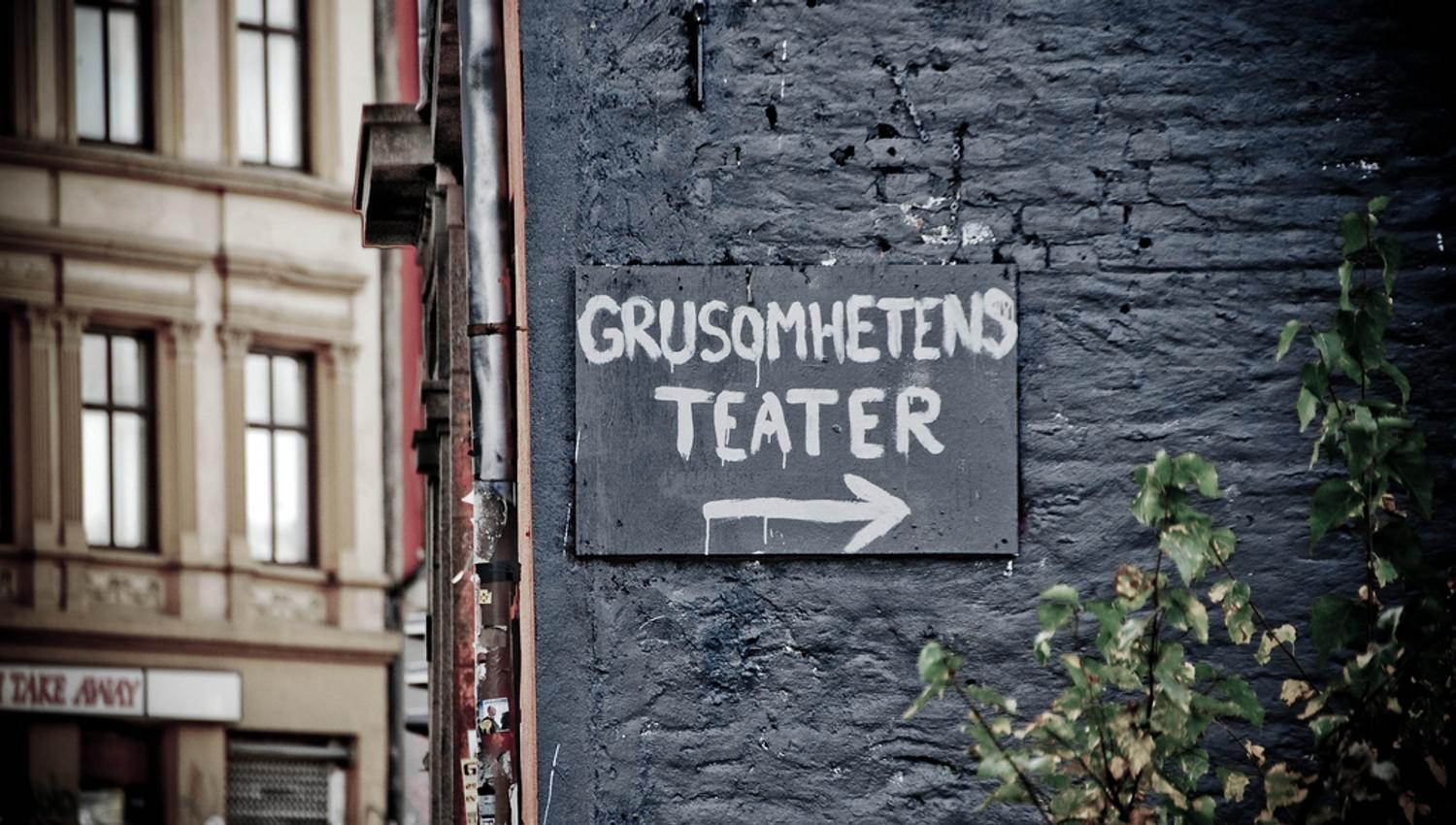 Svart murvegg med skilt til Grusomhetens teater.