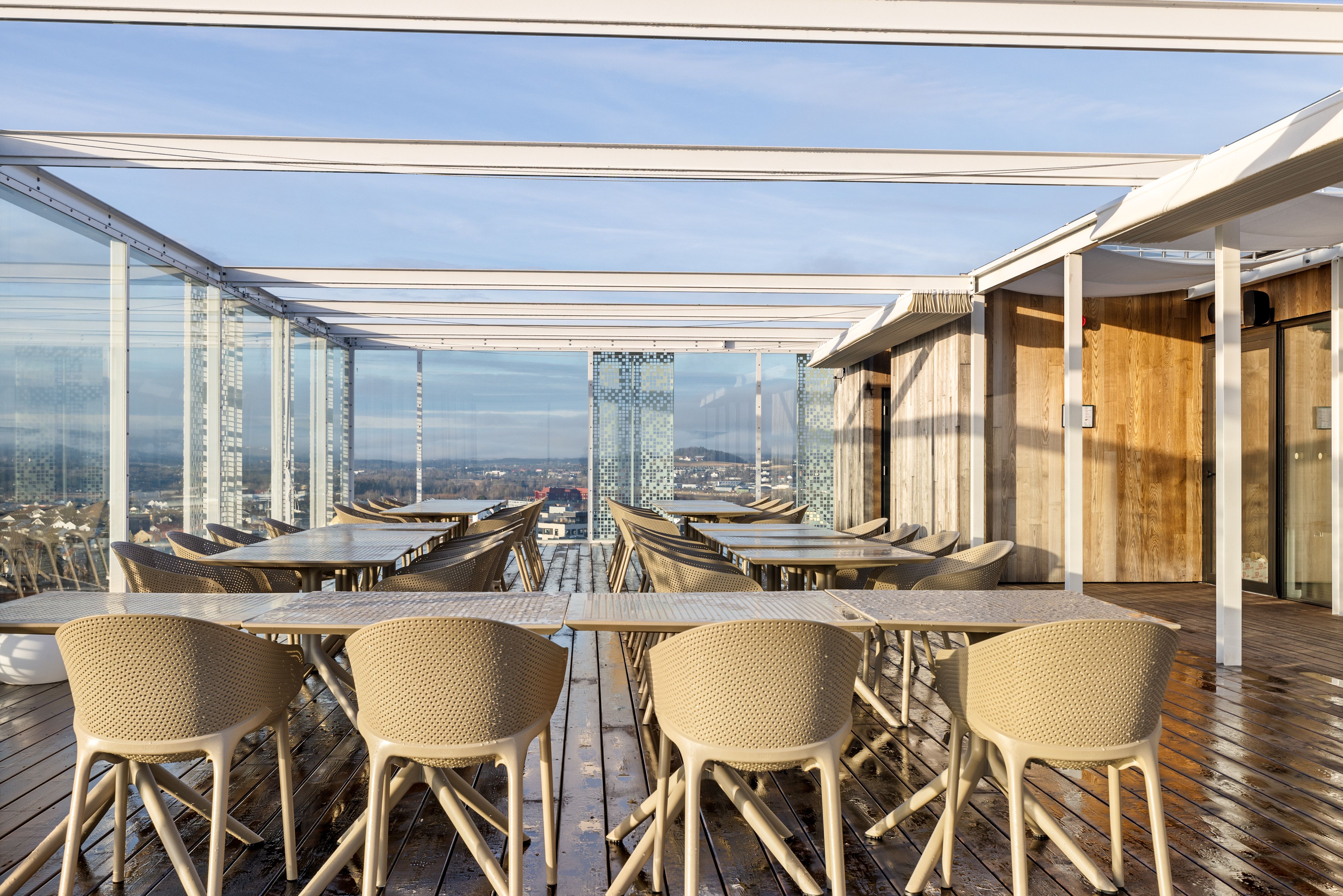 bilde med bord og stoler på en takterrasse