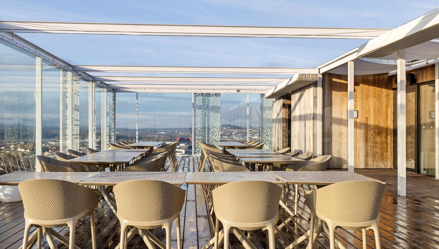 bilde med bord og stoler på en takterrasse