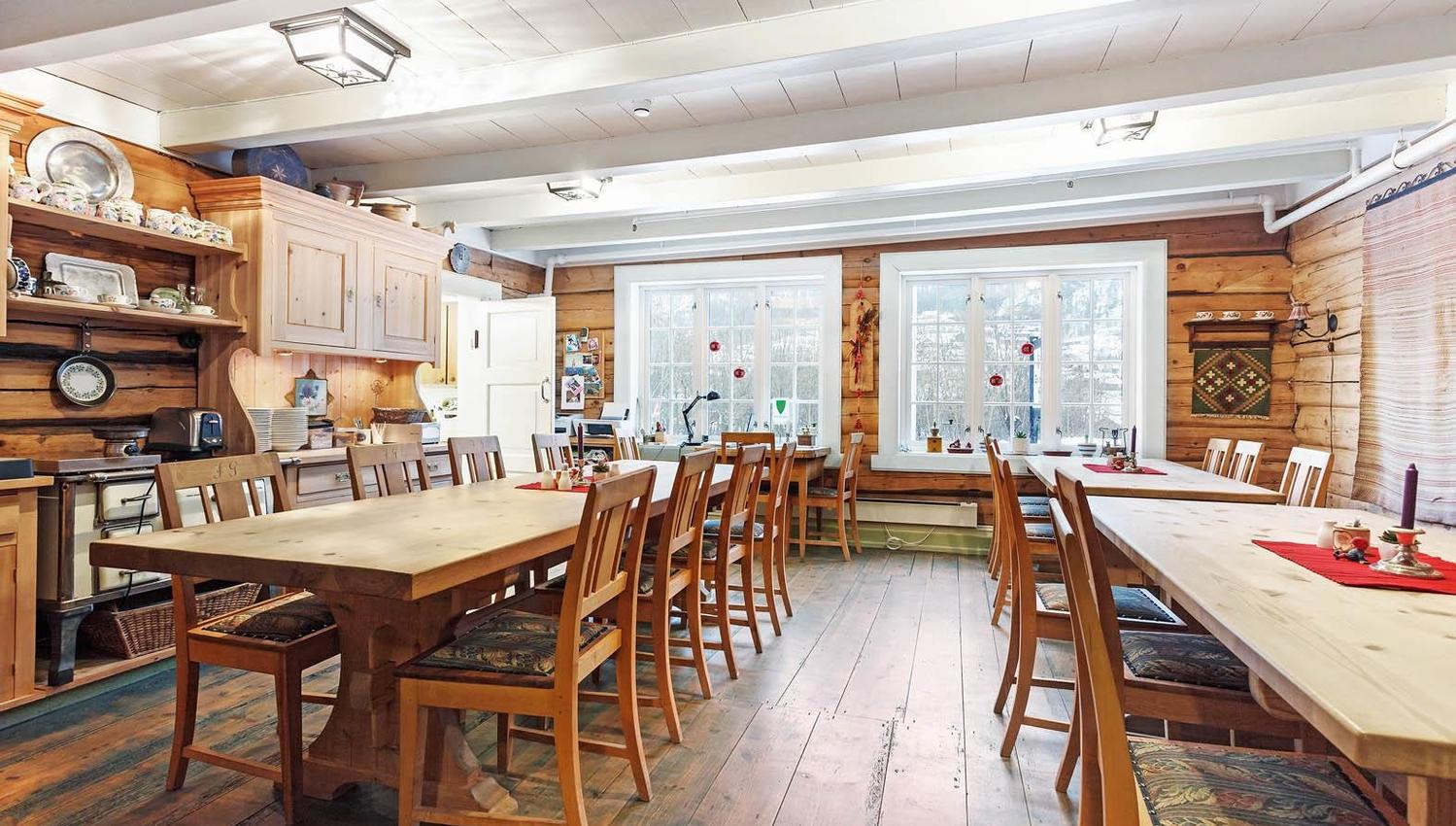 Traditional dining hall with wooden log walls and long tables at Jaunsen Guesthouse in Hardanger.