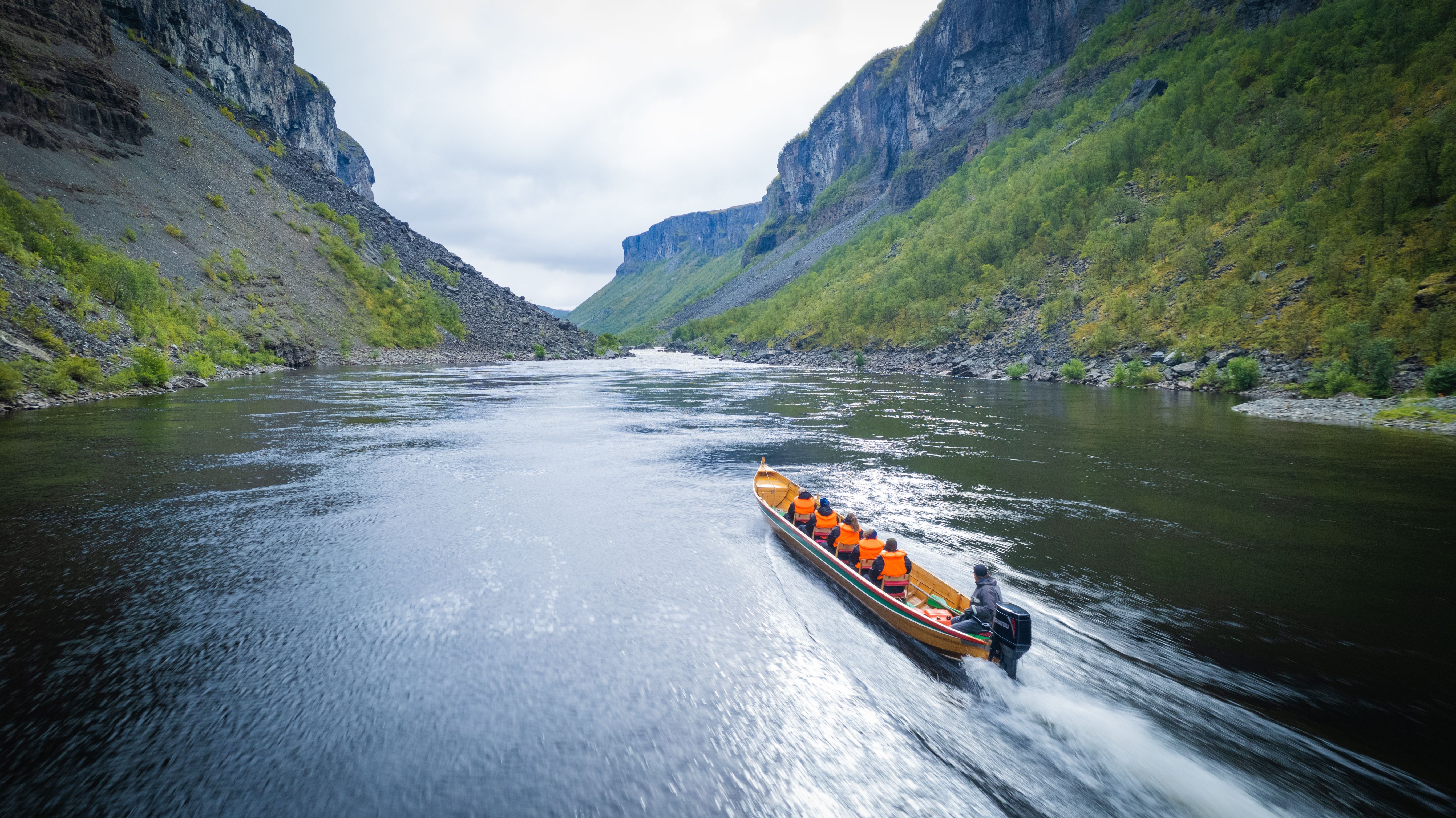 Experience the serene beauty of nature as a boat navigates a tranquil river, flanked by majestic cliffs and lush greenery. Perfect for adventure seekers and nature lovers alike!