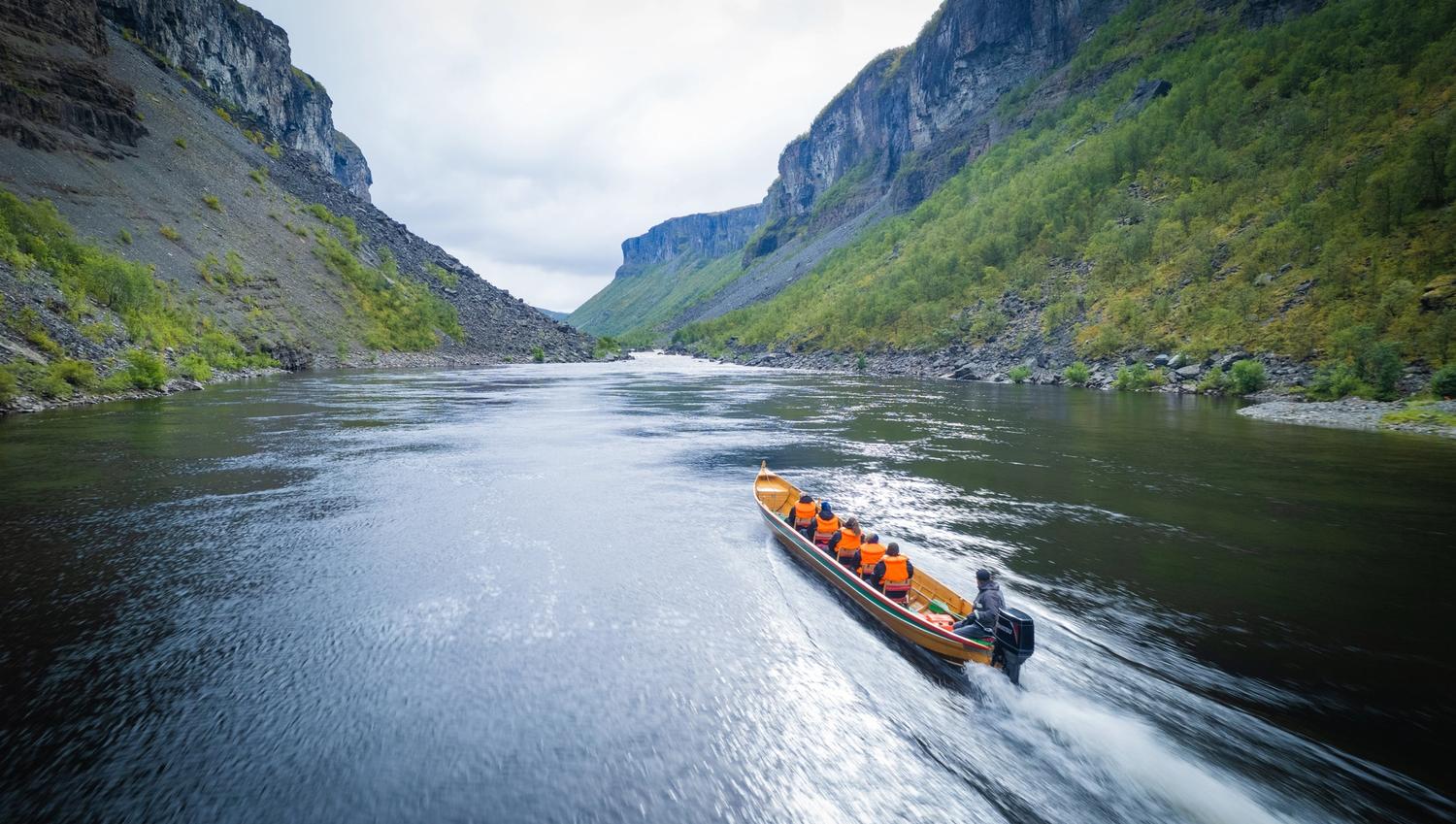 Experience the serene beauty of nature as a boat navigates a tranquil river, flanked by majestic cliffs and lush greenery. Perfect for adventure seekers and nature lovers alike!