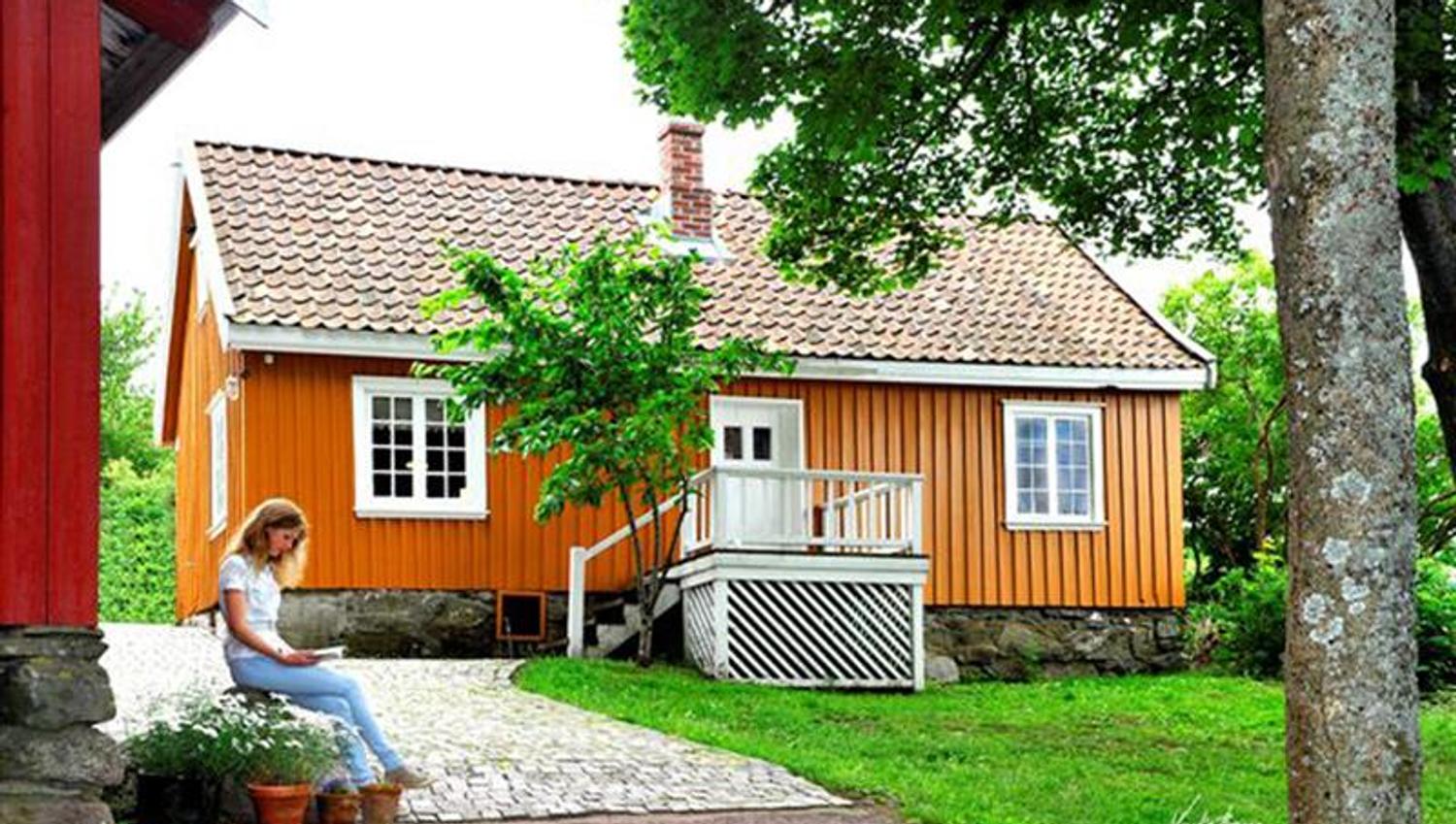 Munch sitt hus sett fra oppkjørselen. Jente sitter foran huset.