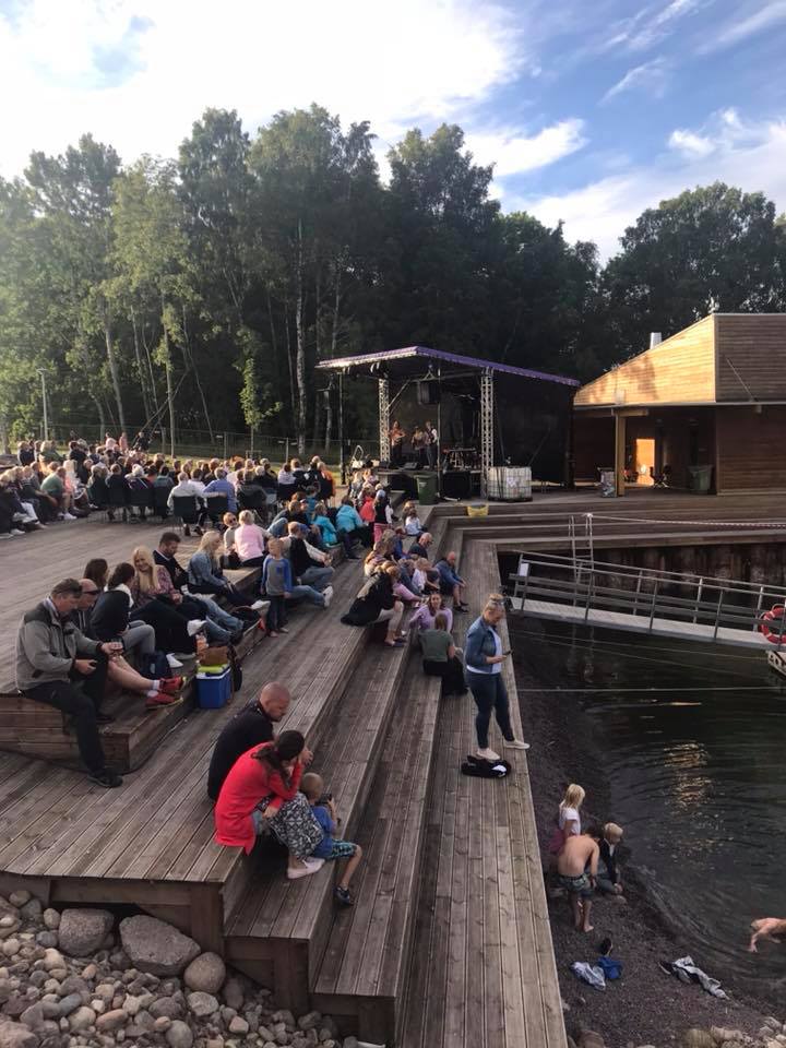 Mennesker sitter på platting ved vannet