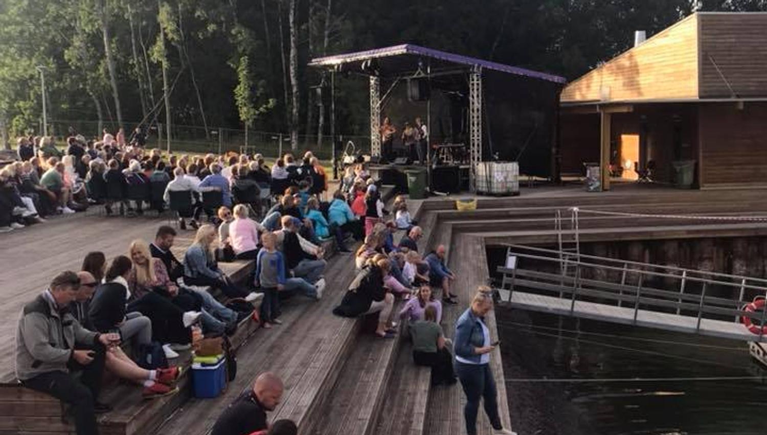 Mennesker sitter på platting ved vannet