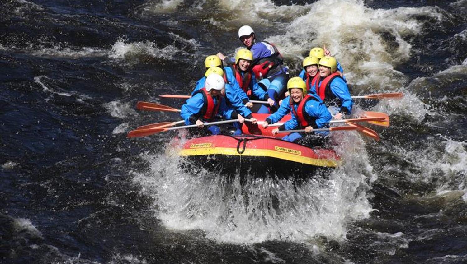 Rafting, med mennesker i blå brakt og gule hjelmer
