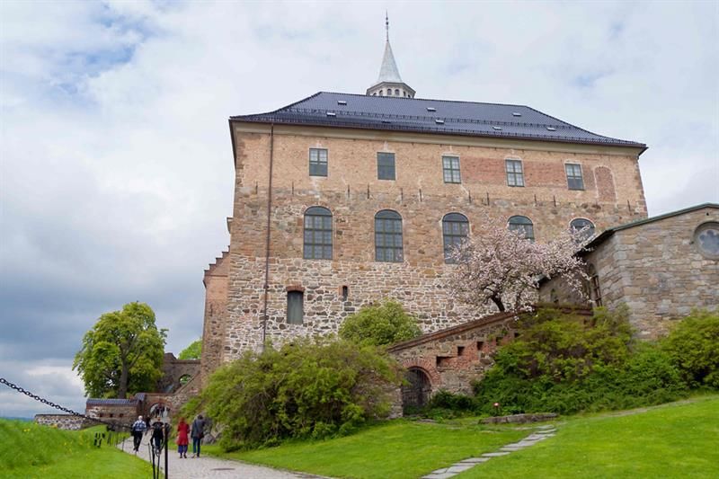 Akershus slott sett fra froskeperspektiv, med mennesker som går forbi på venstre hånd.