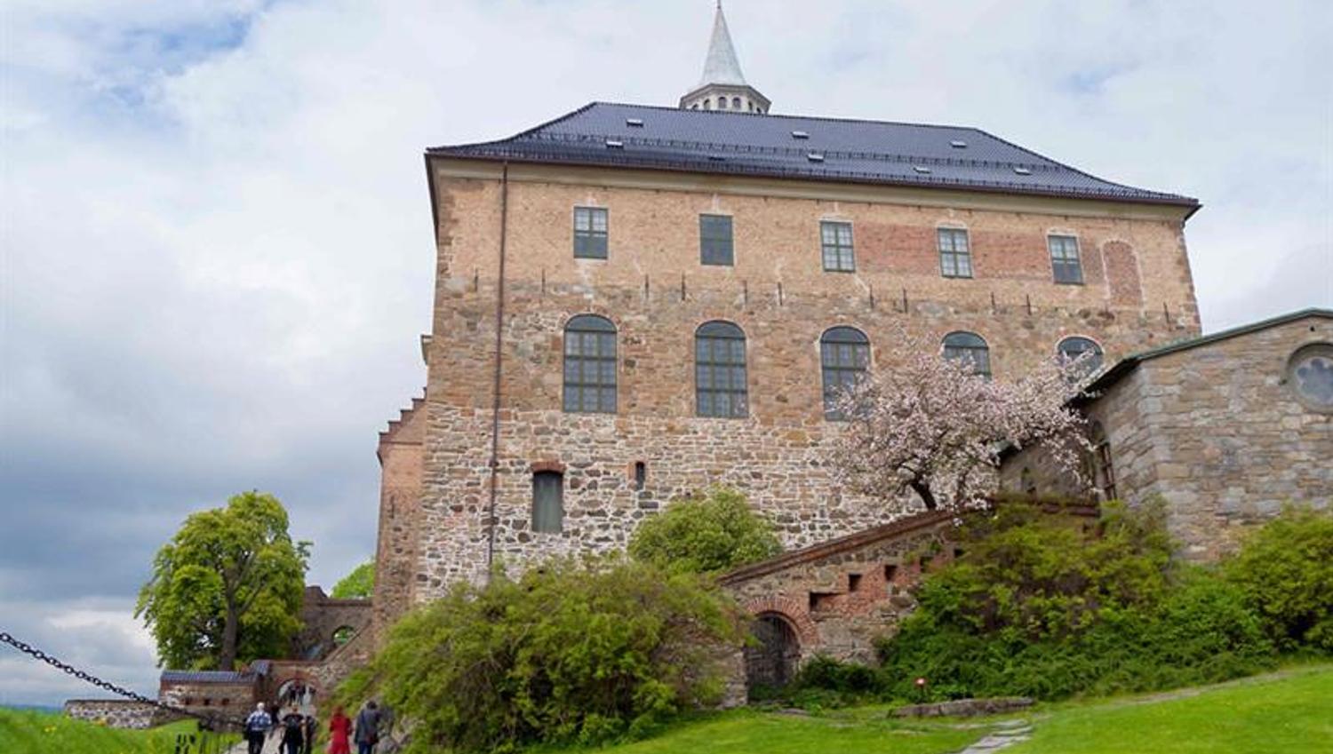 Akershus slott sett fra froskeperspektiv, med mennesker som går forbi på venstre hånd.