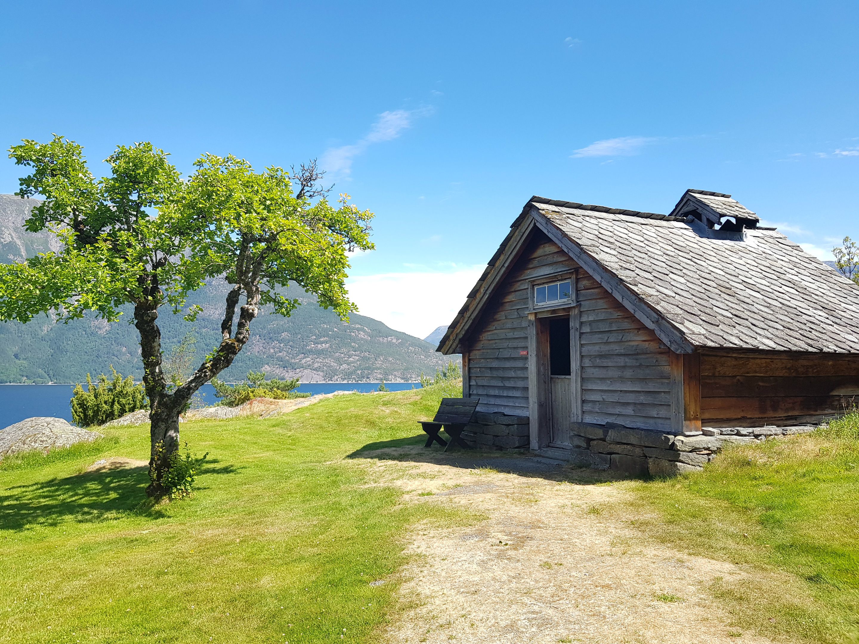 Gamal tømrahytte i friluftsmuseet med utsikt over fjord og fjell i Hardanger.