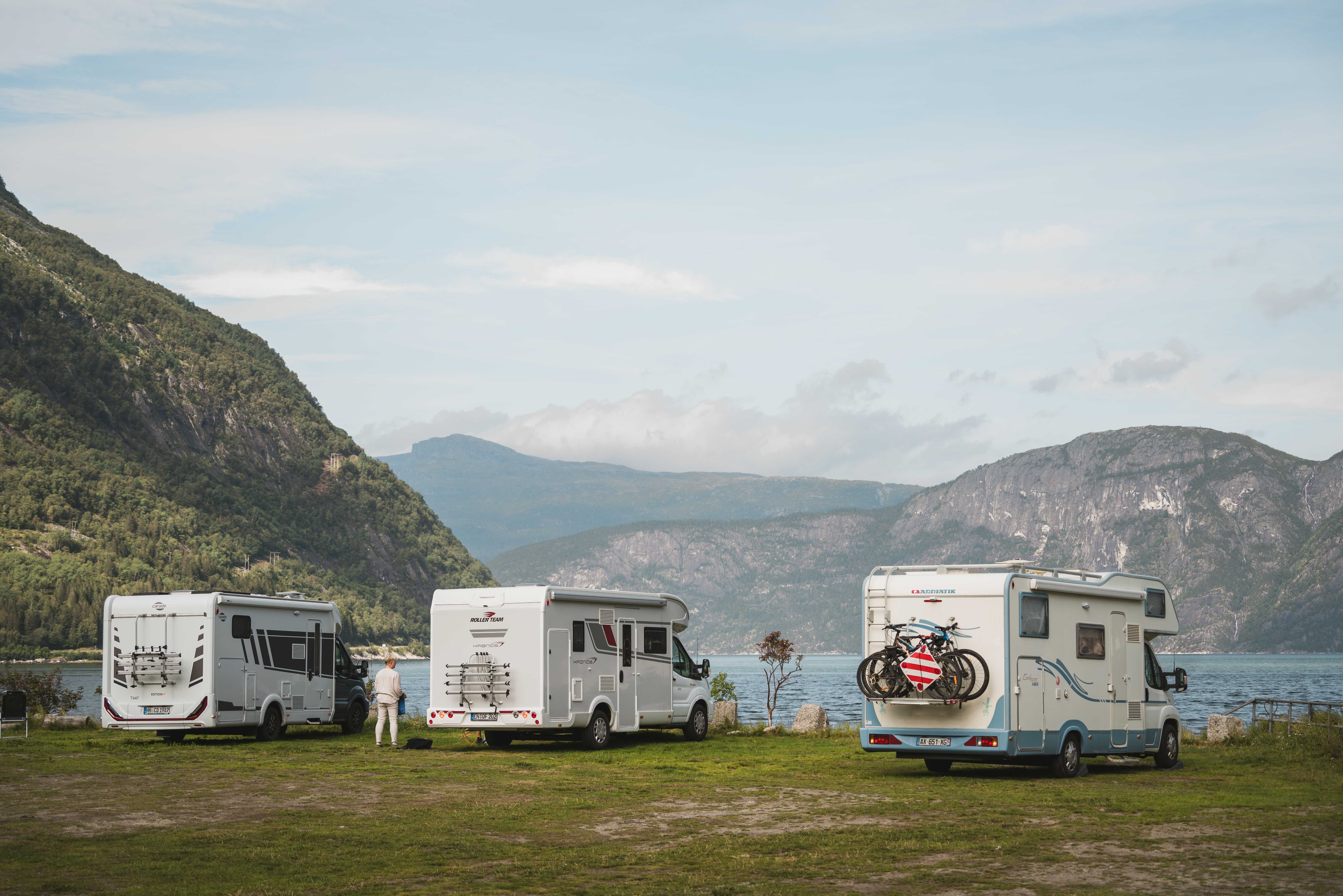 Three mobile homes stand at the edge of the fjord at the campsite.