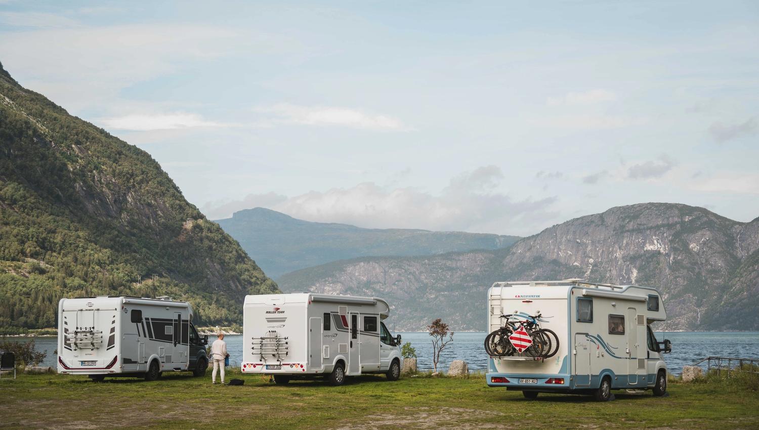 Three mobile homes stand at the edge of the fjord at the campsite.