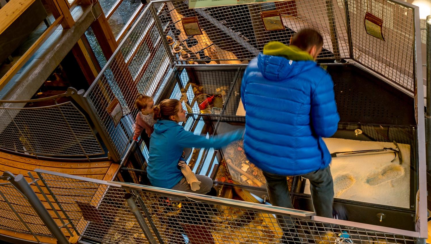A family looks at parts of the exhibition that are mounted on the floor.
