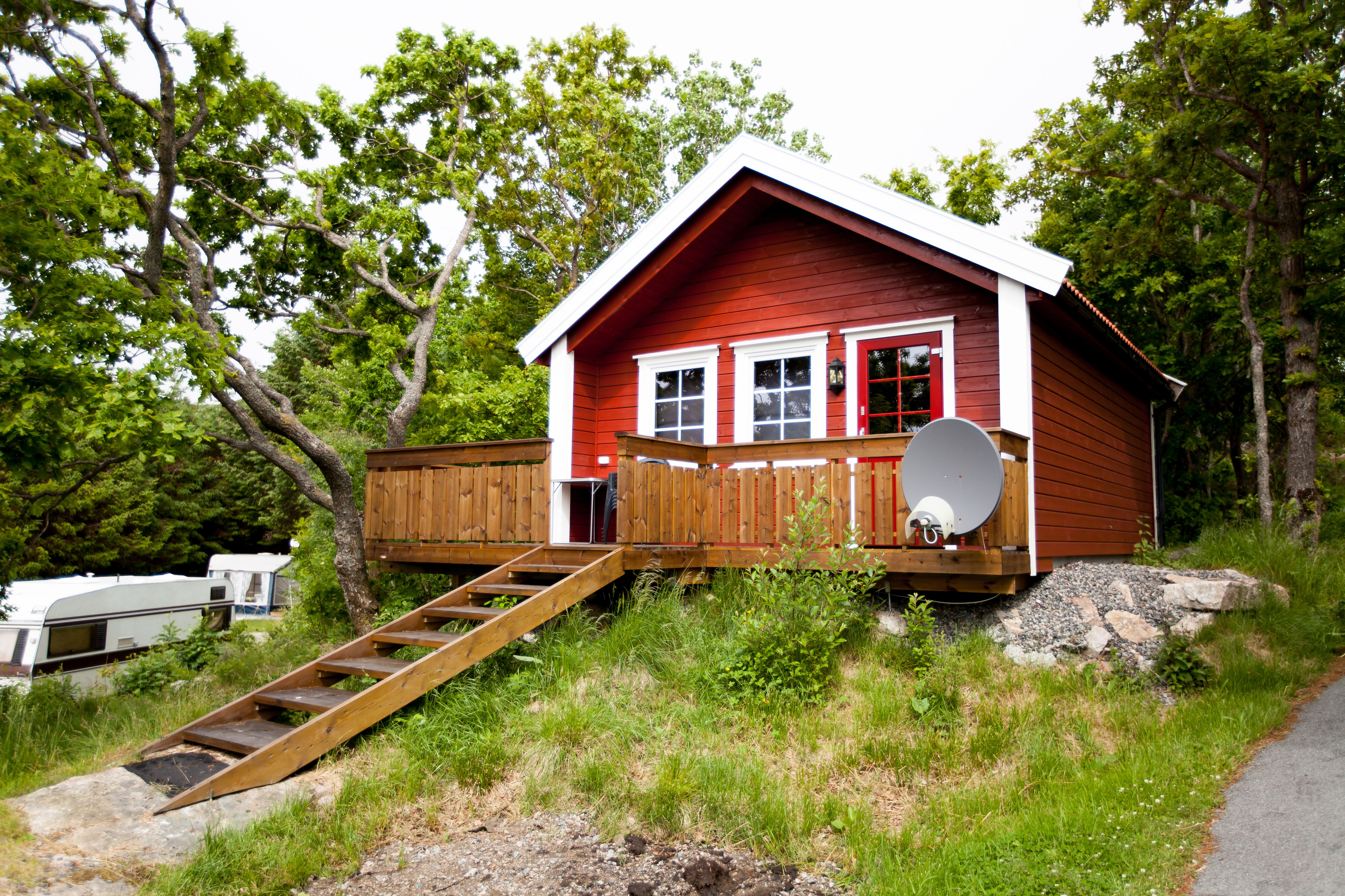 Lindesnes Camping og Hytteutleie - Rød hytte med hvite karmer, har også en terrasse med trapp inn til hytta.