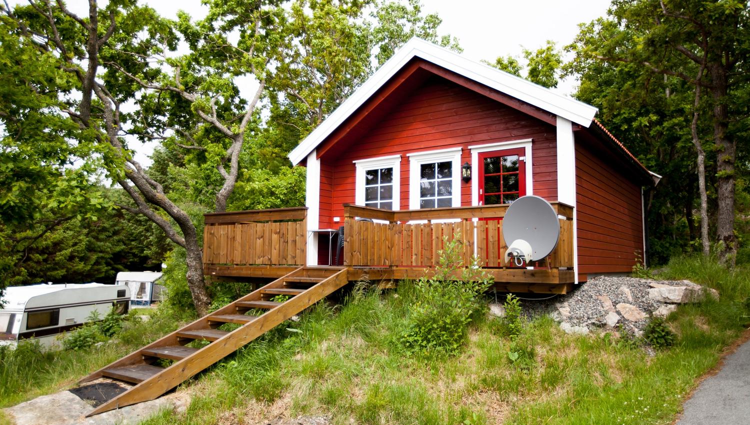 Lindesnes Camping og Hytteutleie - Rød hytte med hvite karmer, har også en terrasse med trapp inn til hytta.