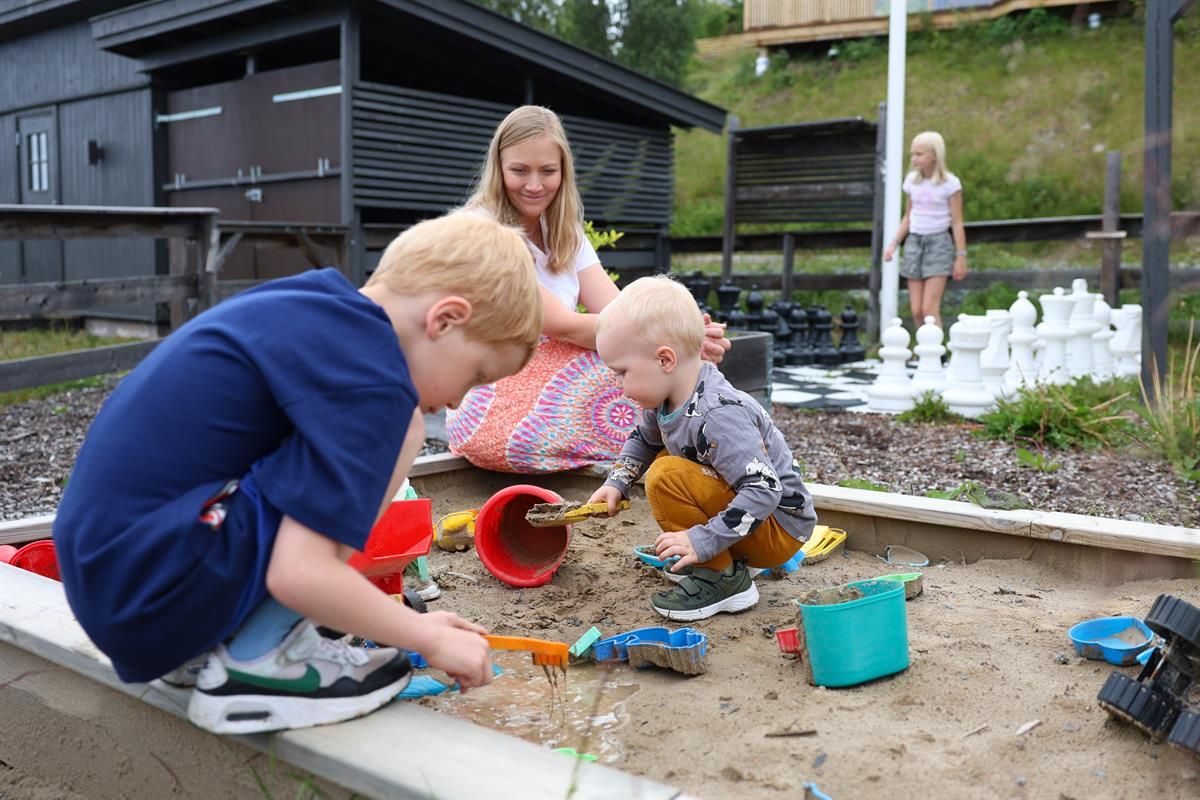 Children playing with sand and toys in an outdoor sandbox.