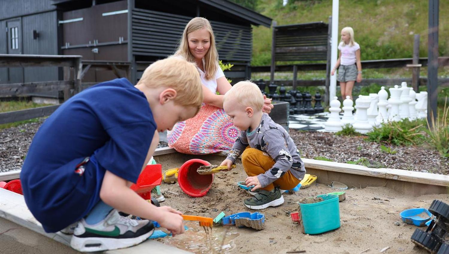 Children playing with sand and toys in an outdoor sandbox.