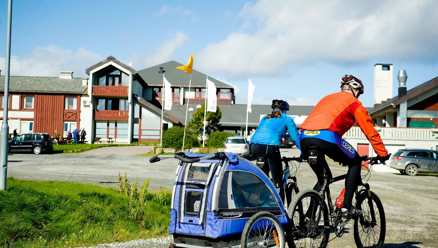 Syklister med sykkeltilhenger utenfor Oset Fjellhotell