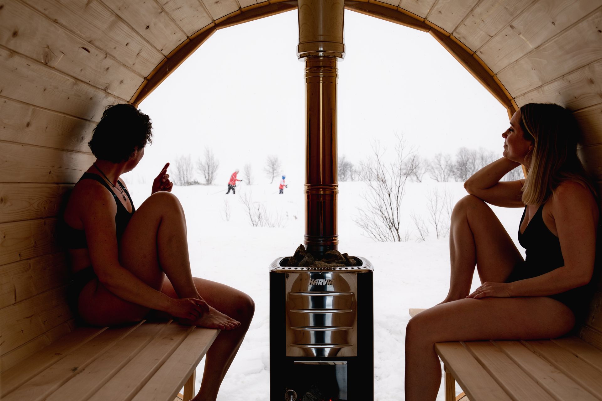Two women are sitting  inside the sauna. 