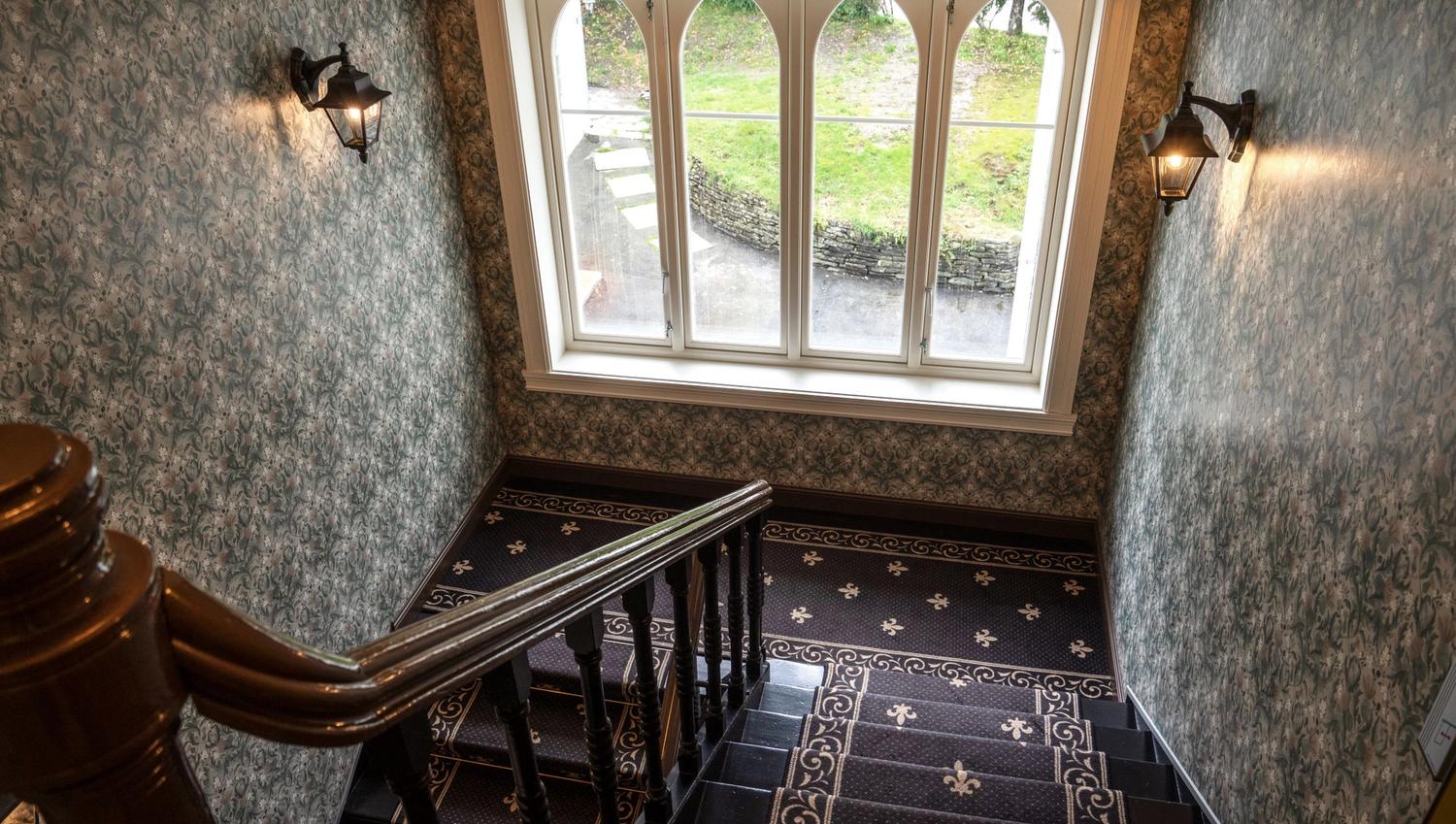 Sjarmerande historisk trapp i Thon Hotel Sandven, med vakre fliser og utsyn mot hagen.