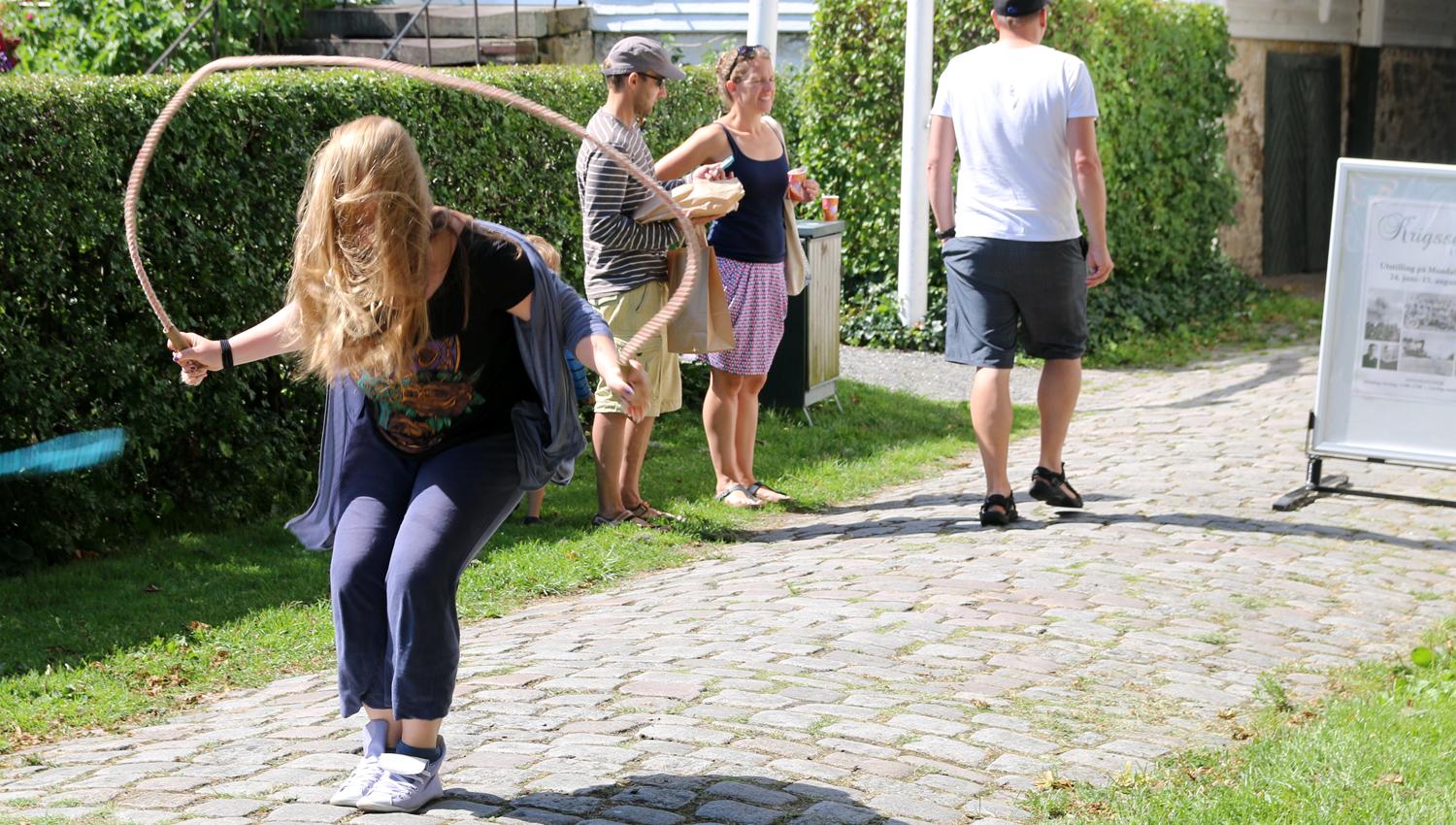 En jente som hopper i tau, og 3 andre i bakgrunnen og ser på noe annet