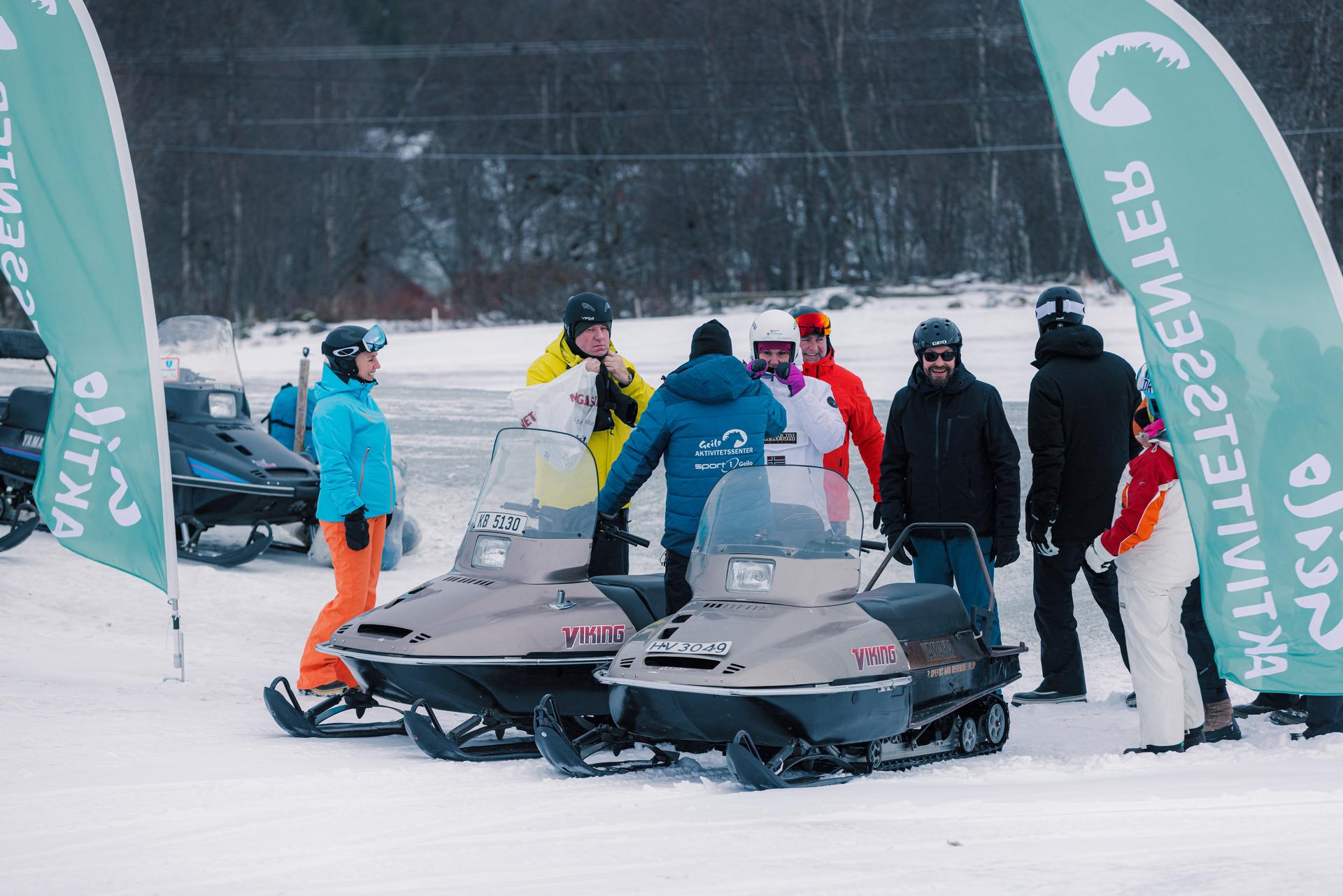 En gruppe mennesker prater og hygger seg etter en flott snøscootertur.