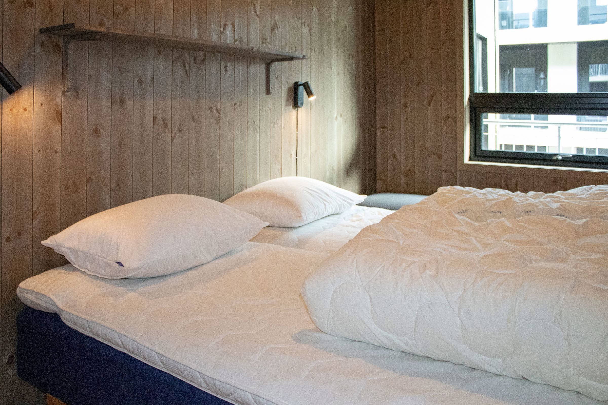 A bed with pillows and a lamp in a room.